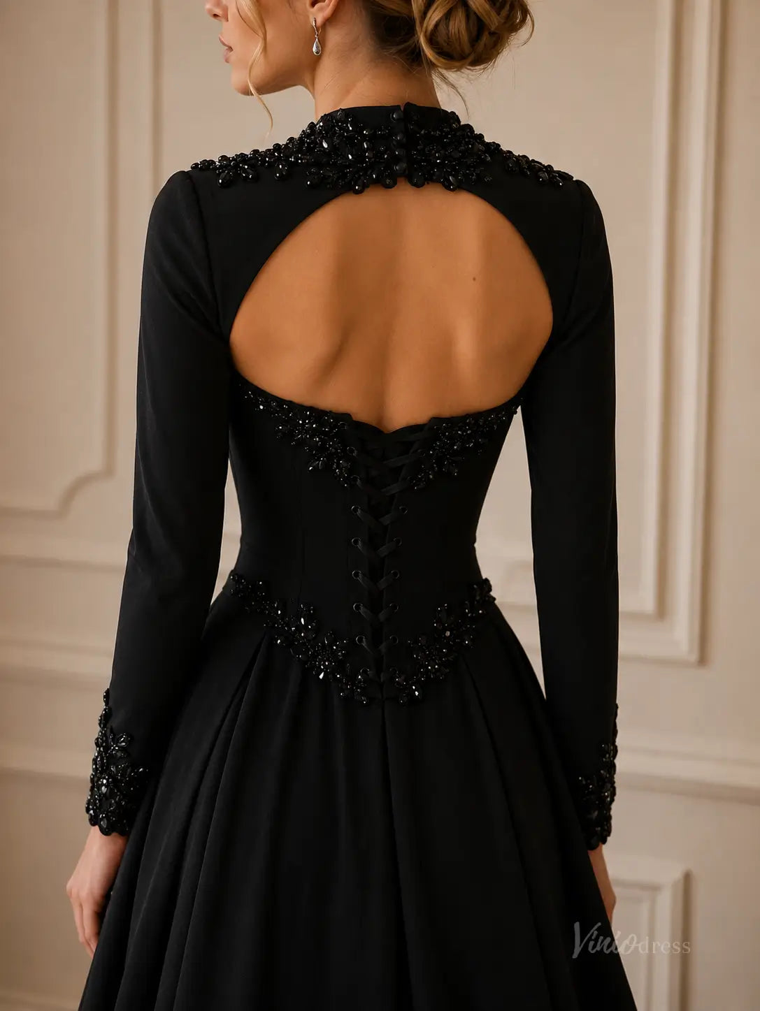 Black crepe long-sleeve gown with a keyhole back, intricate beaded embellishments, and a corset-style lace-up bodice.