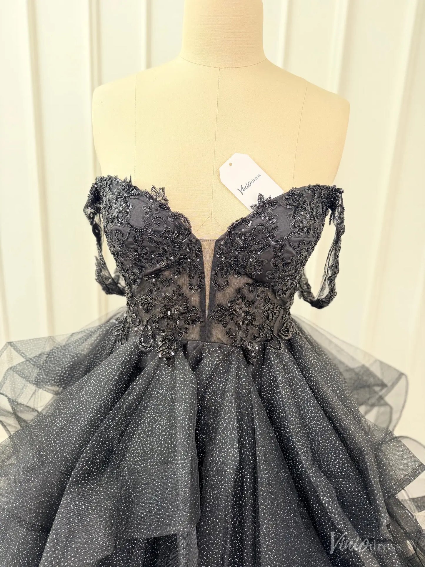 Black off-shoulder ball gown with a corset bodice, illusion V-neck, and shimmering glitter tulle ruffle skirt.