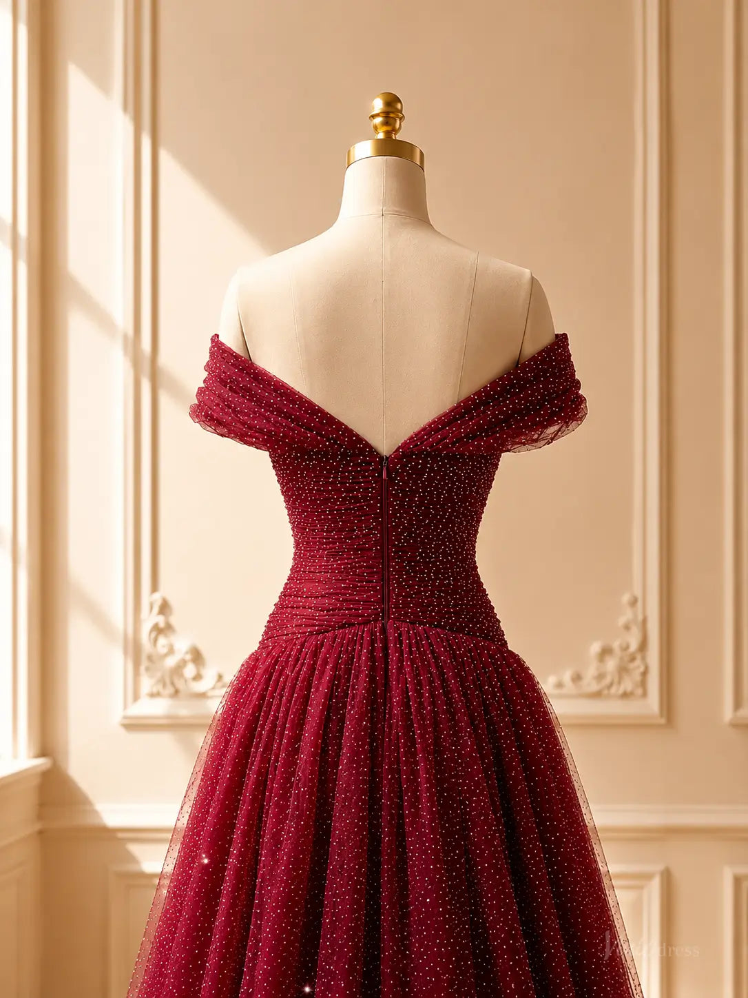 Burgundy sparkly tulle ball gown with an off-shoulder sweetheart neckline and ruched bodice on a mannequin.