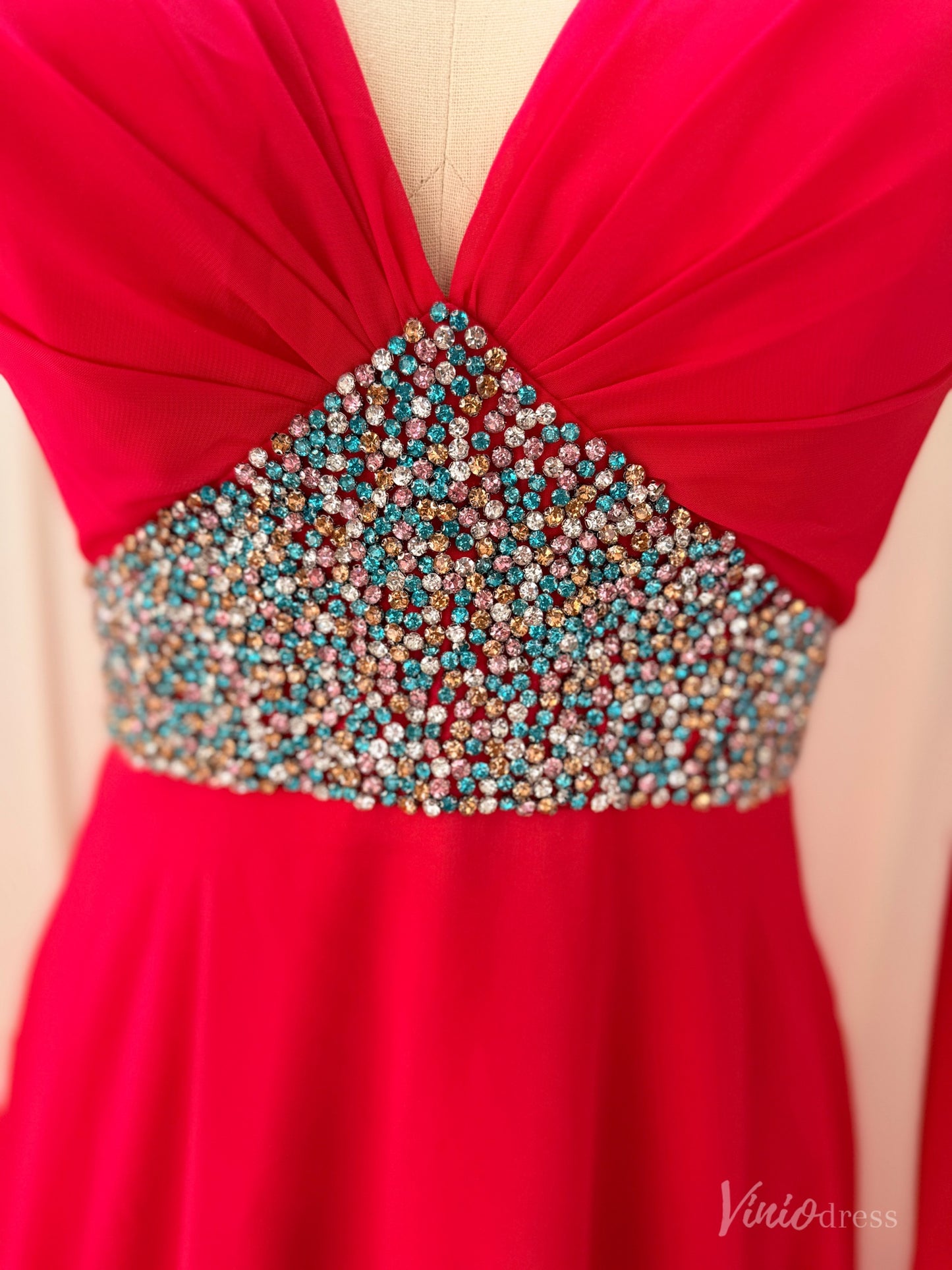 Crimson red chiffon gown featuring a V-neckline and a waistline adorned with multicolored sparkling crystals.