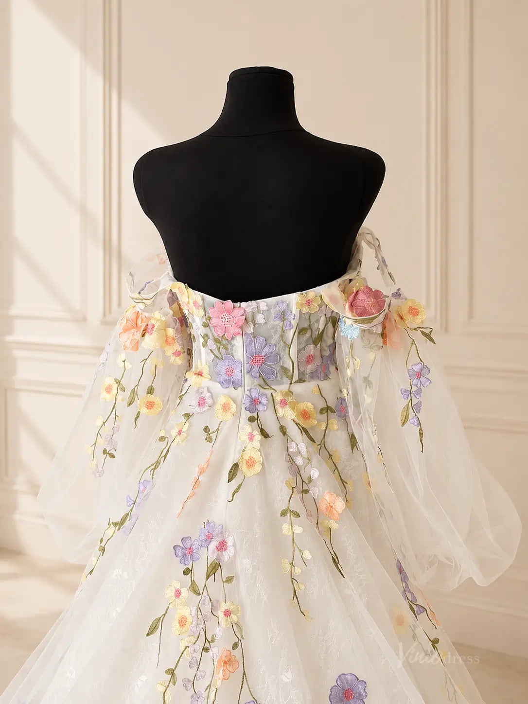 White off-the-shoulder wedding dress featuring sheer puff sleeves and colorful 3D floral embroidery on lace fabric.