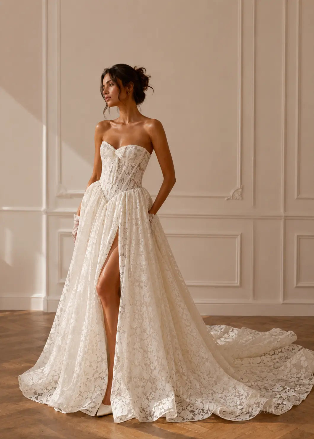 Strapless white lace wedding dress with a corset bodice, high leg slit, and a long flowing train.