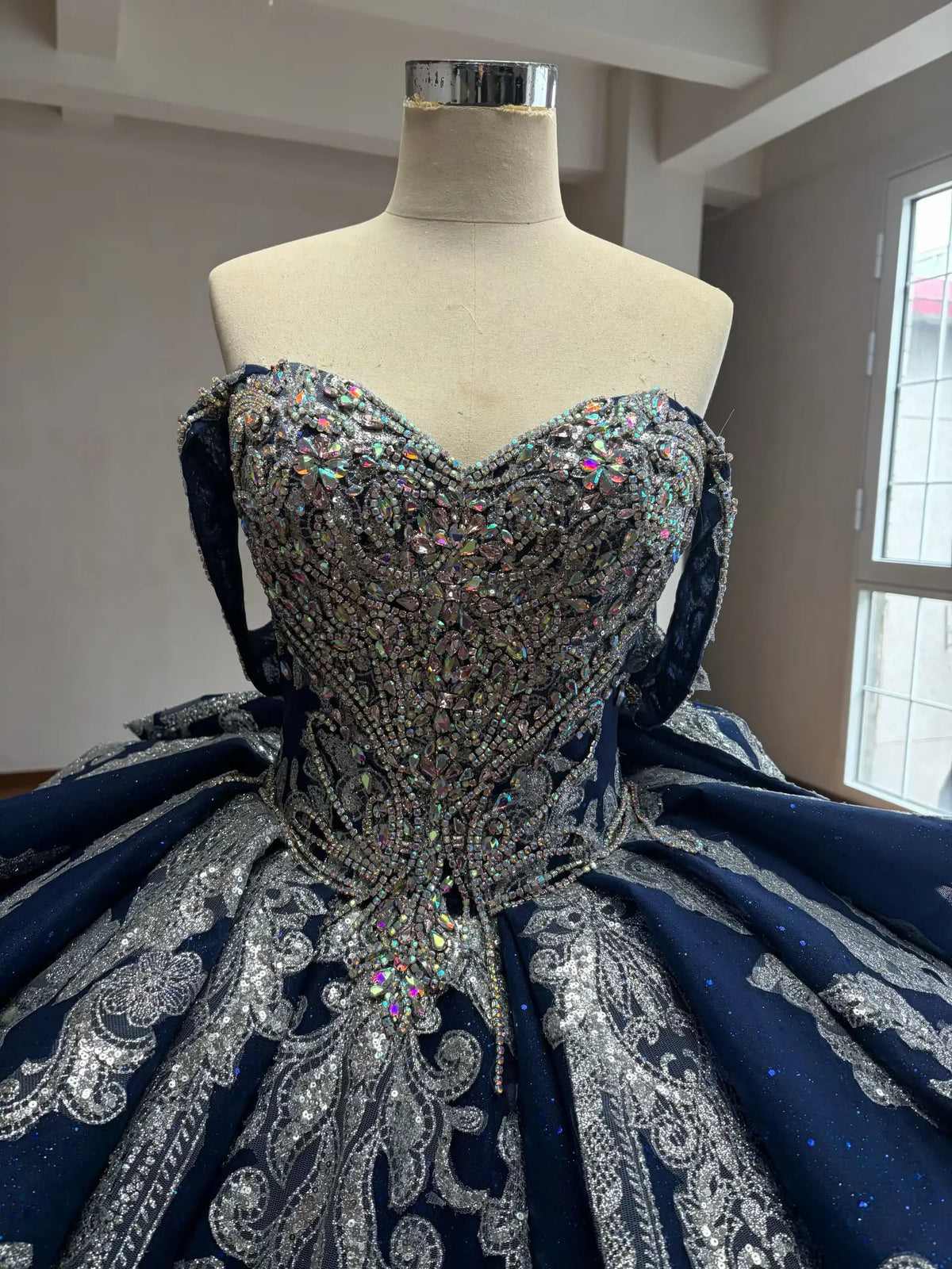 Navy blue ball gown featuring a crystal-encrusted corset bodice and intricate silver baroque embroidery on a full skirt.