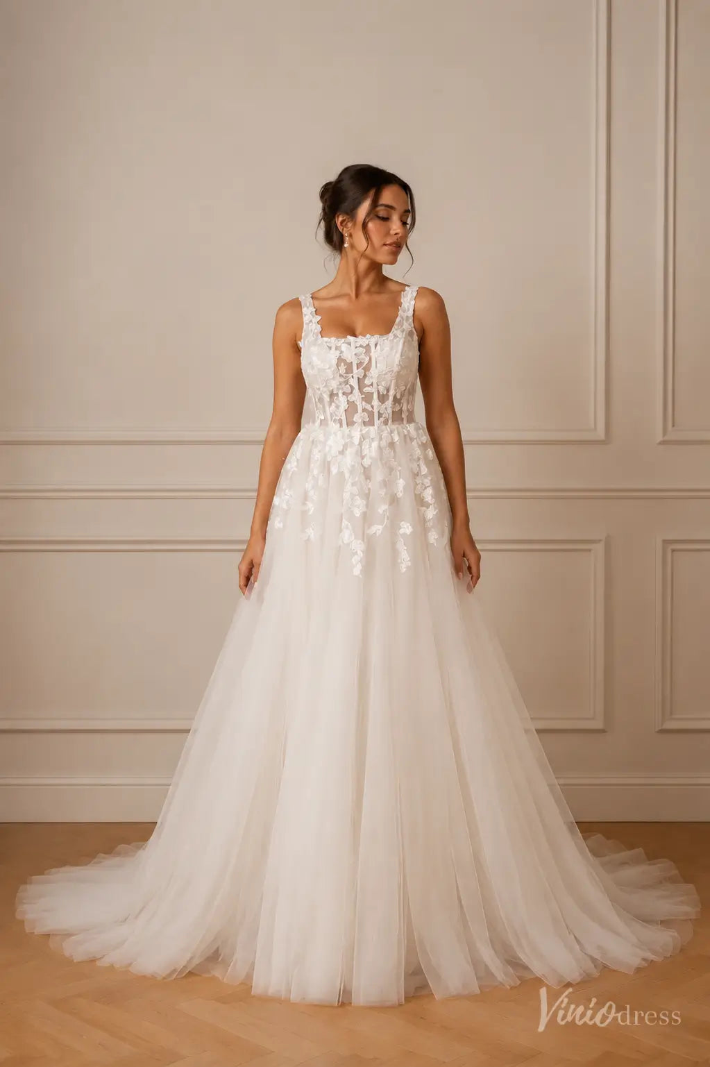 White A-line wedding dress with a square neckline, sheer corset bodice, and delicate floral lace appliqué on tulle.