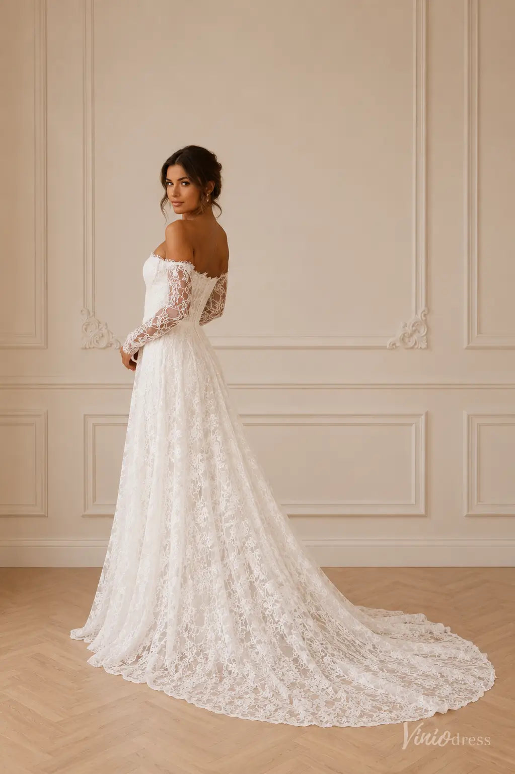 Off-the-shoulder white lace wedding dress with long sleeves and a flowing A-line train.