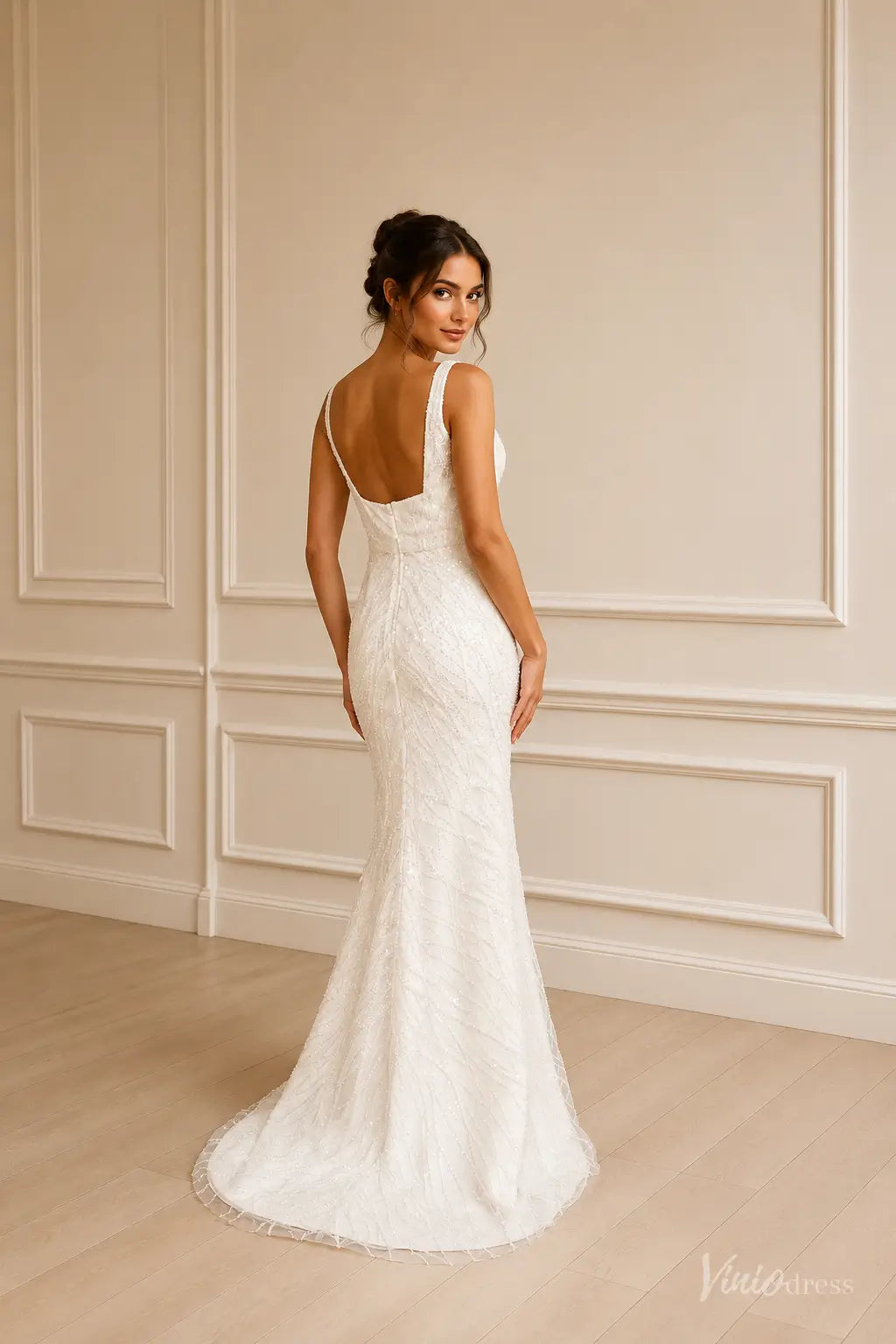White sleeveless mermaid wedding dress with intricate beadwork, a low scoop back, and a subtle floor-length train.