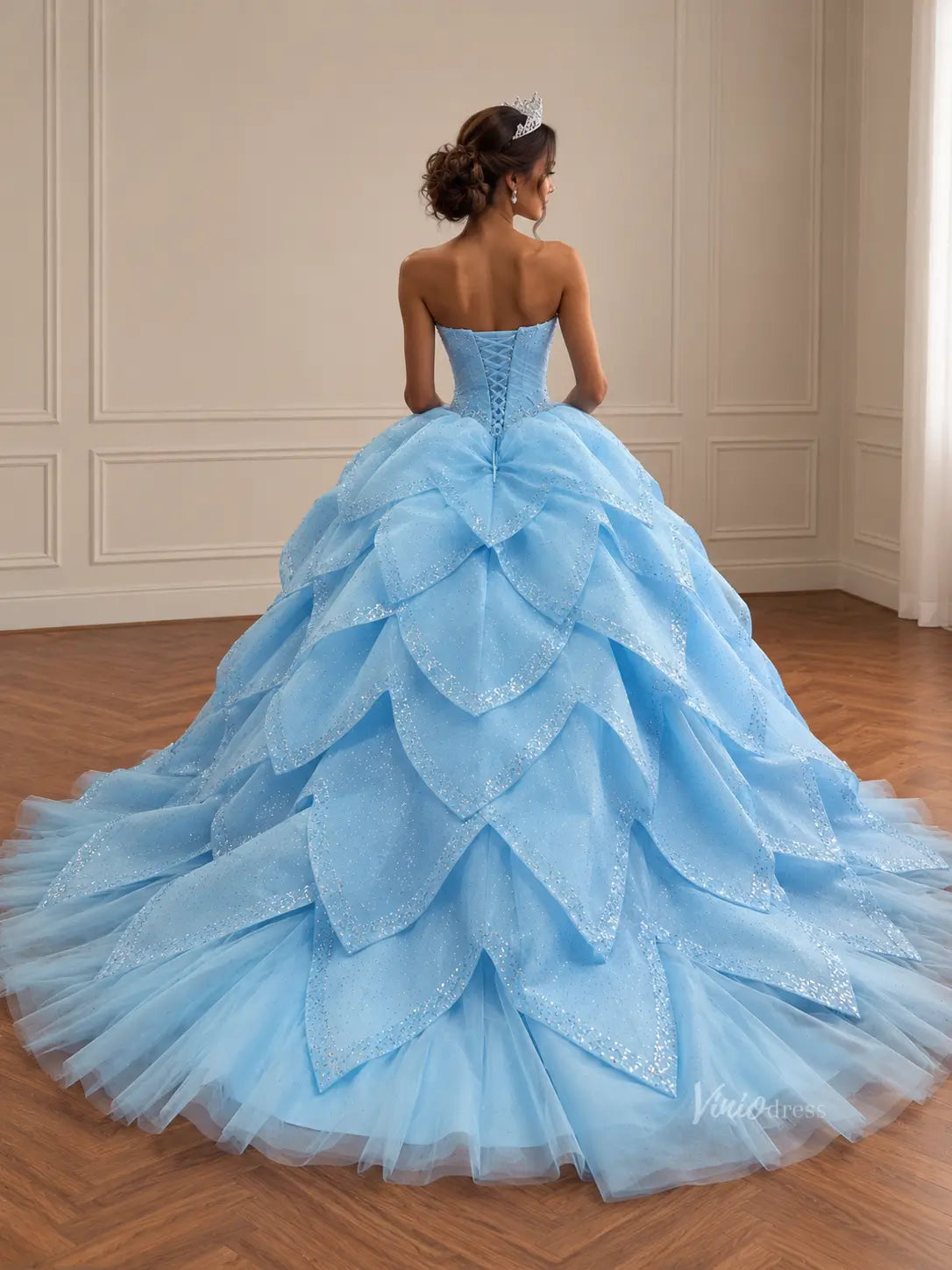 Light blue strapless Quinceañera dress with a glittery corset back and a dramatic, removable petal-layered skirt.