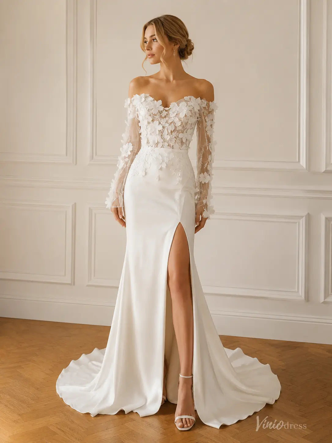 Ivory sheath wedding dress with 3D lace bodice, off-the-shoulder long sleeves, and a high leg slit on a satin skirt.