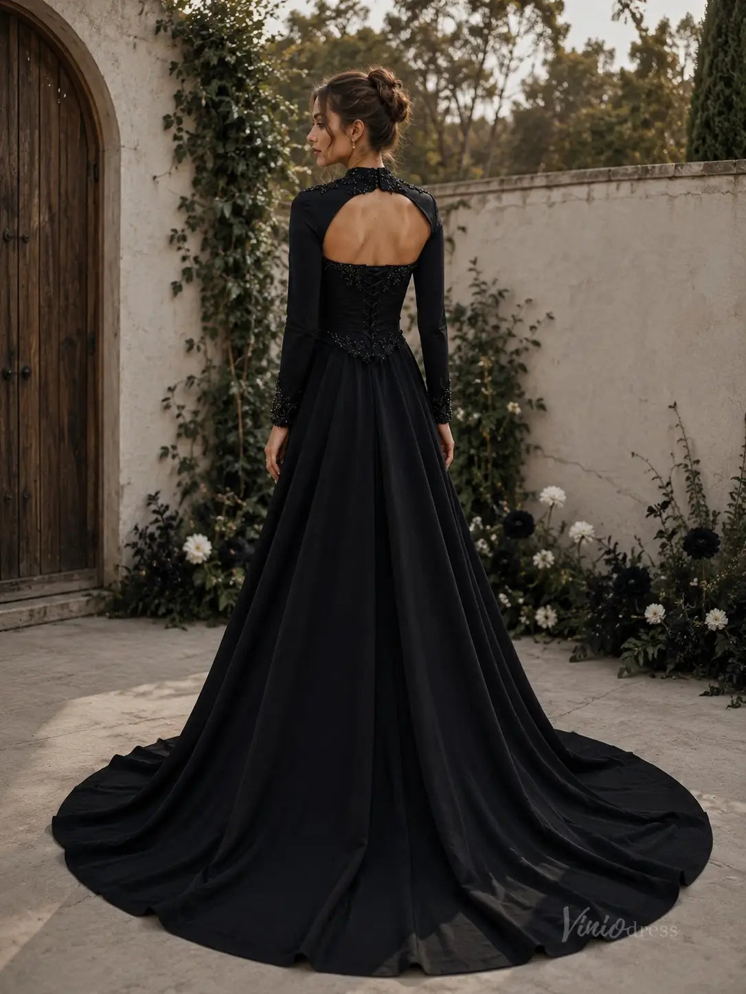 Black crepe wedding dress with long sleeves, open back, corset bodice, and a flowing floor-length train.