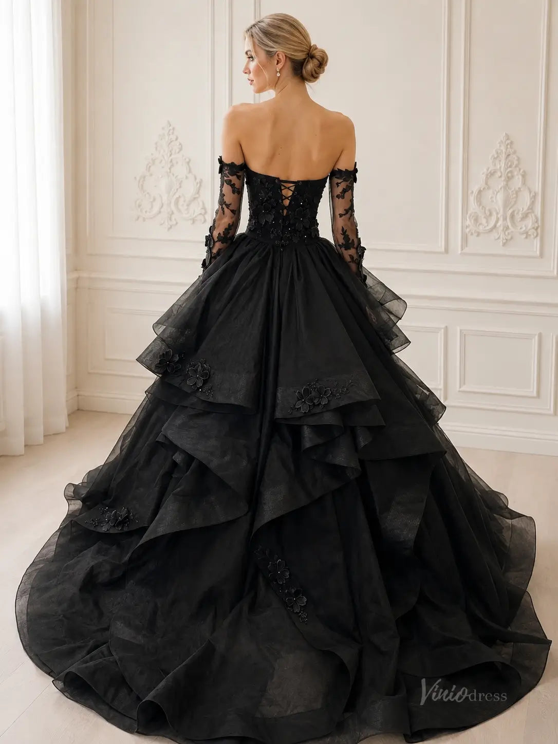 Black off-the-shoulder ball gown with lace sleeves, corset back, and tiered tulle skirt featuring floral appliqués.