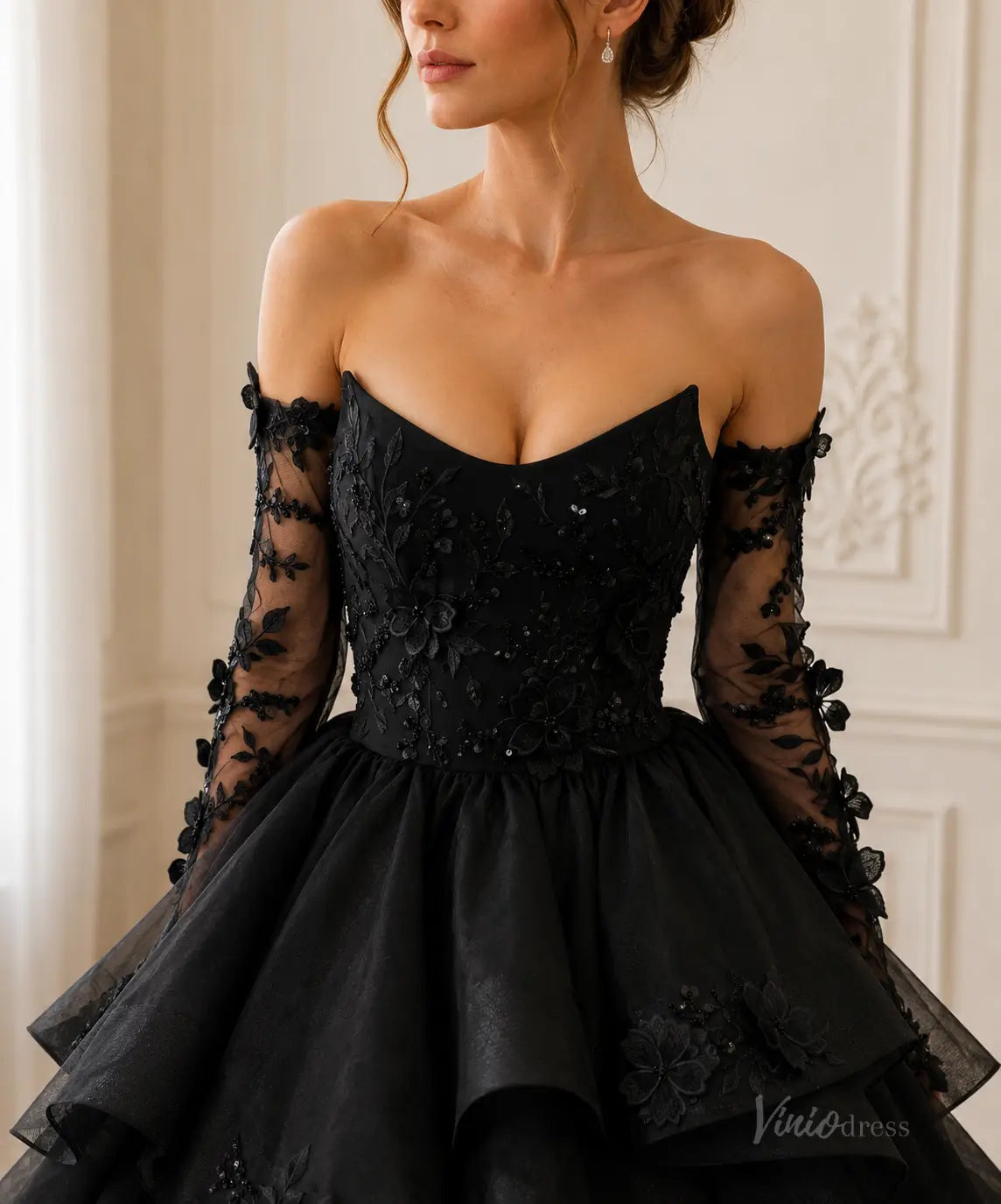 Black off-the-shoulder ball gown with long sheer sleeves, floral lace embroidery, and a voluminous tiered tulle skirt.