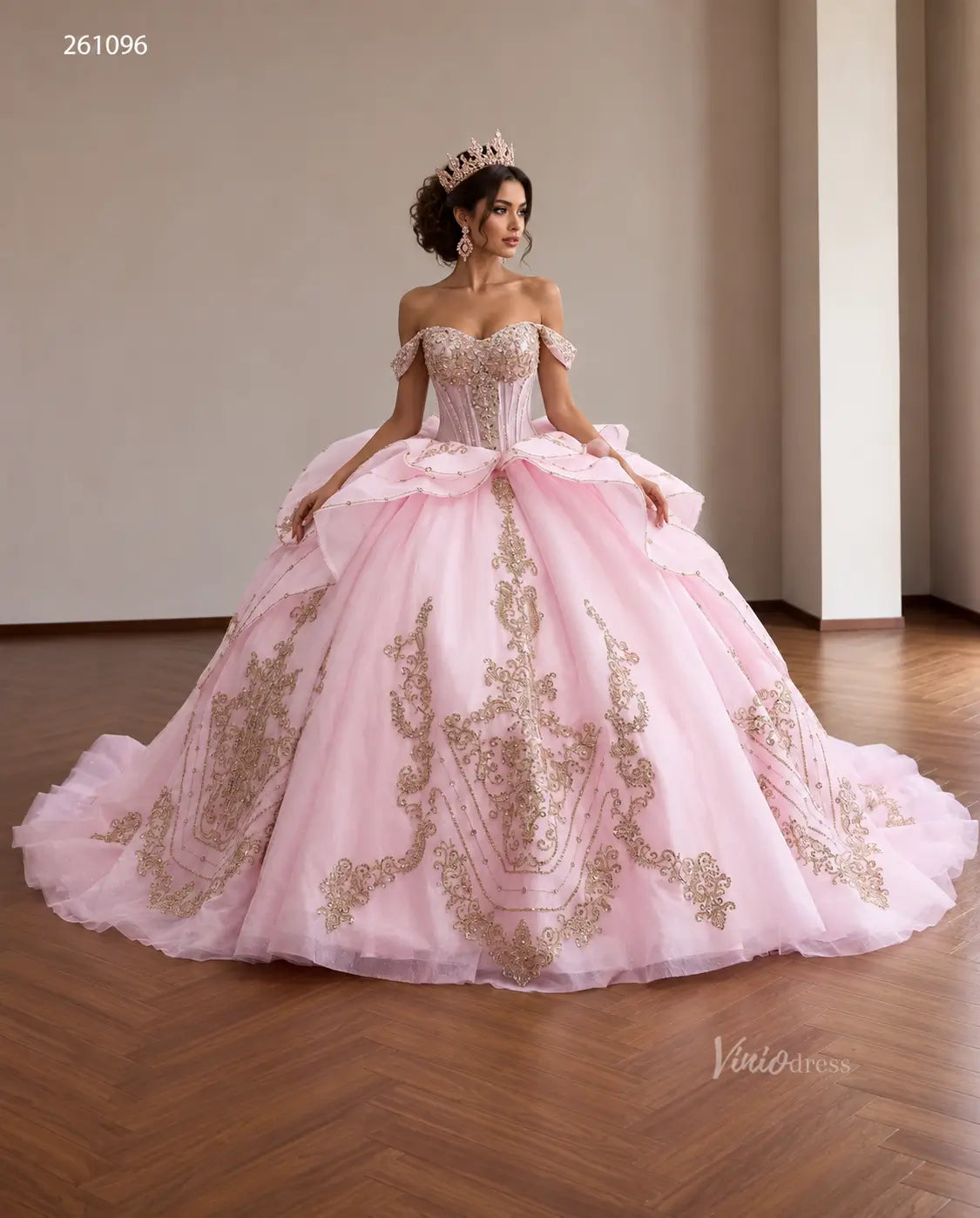 Pink off-shoulder quinceañera ball gown with gold baroque embroidery, crystal corset, and tiered peplum waist.