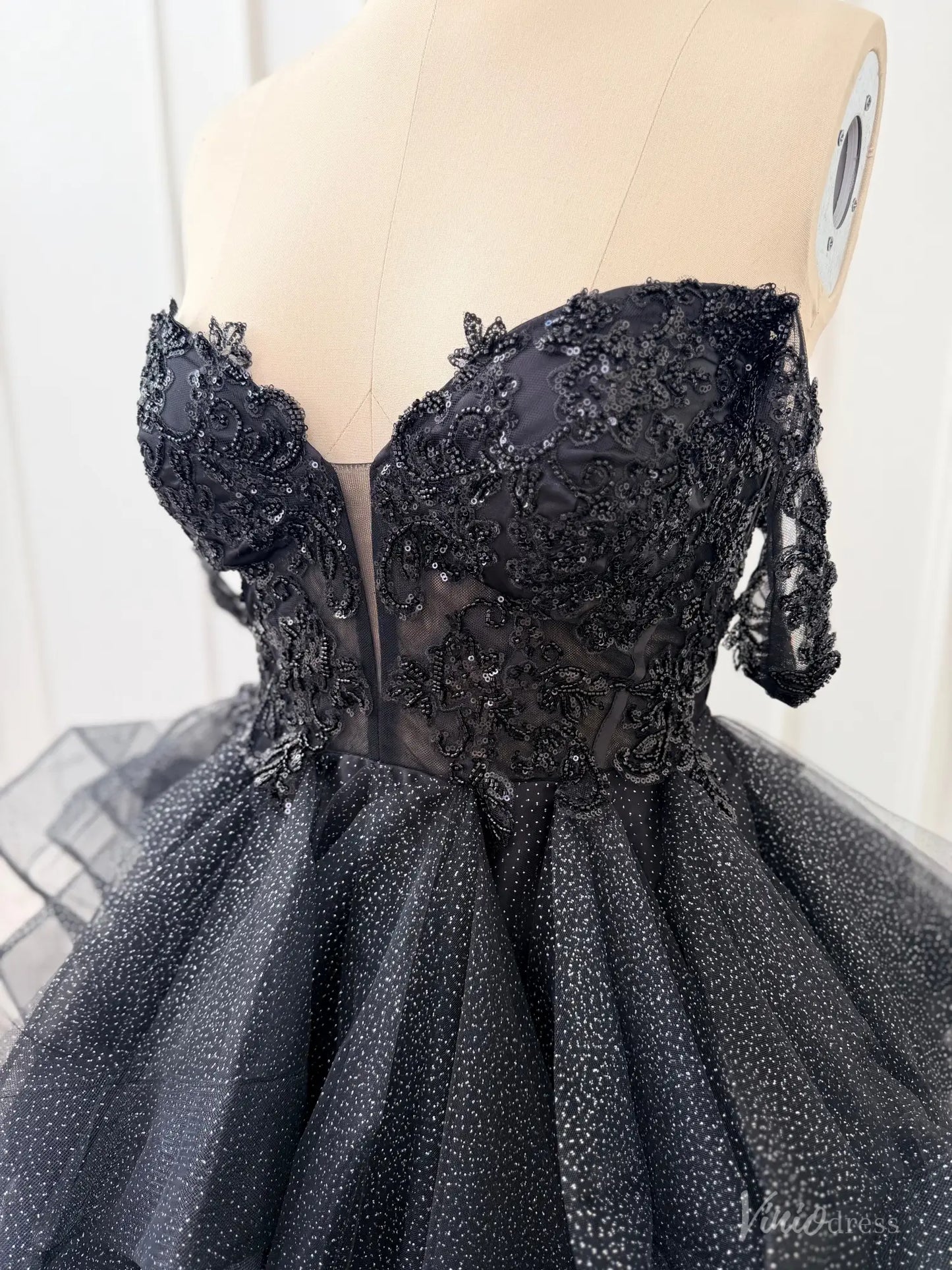Black off-shoulder ball gown with a sequined lace corset bodice, illusion V-neck, and shimmering glitter tulle skirt.