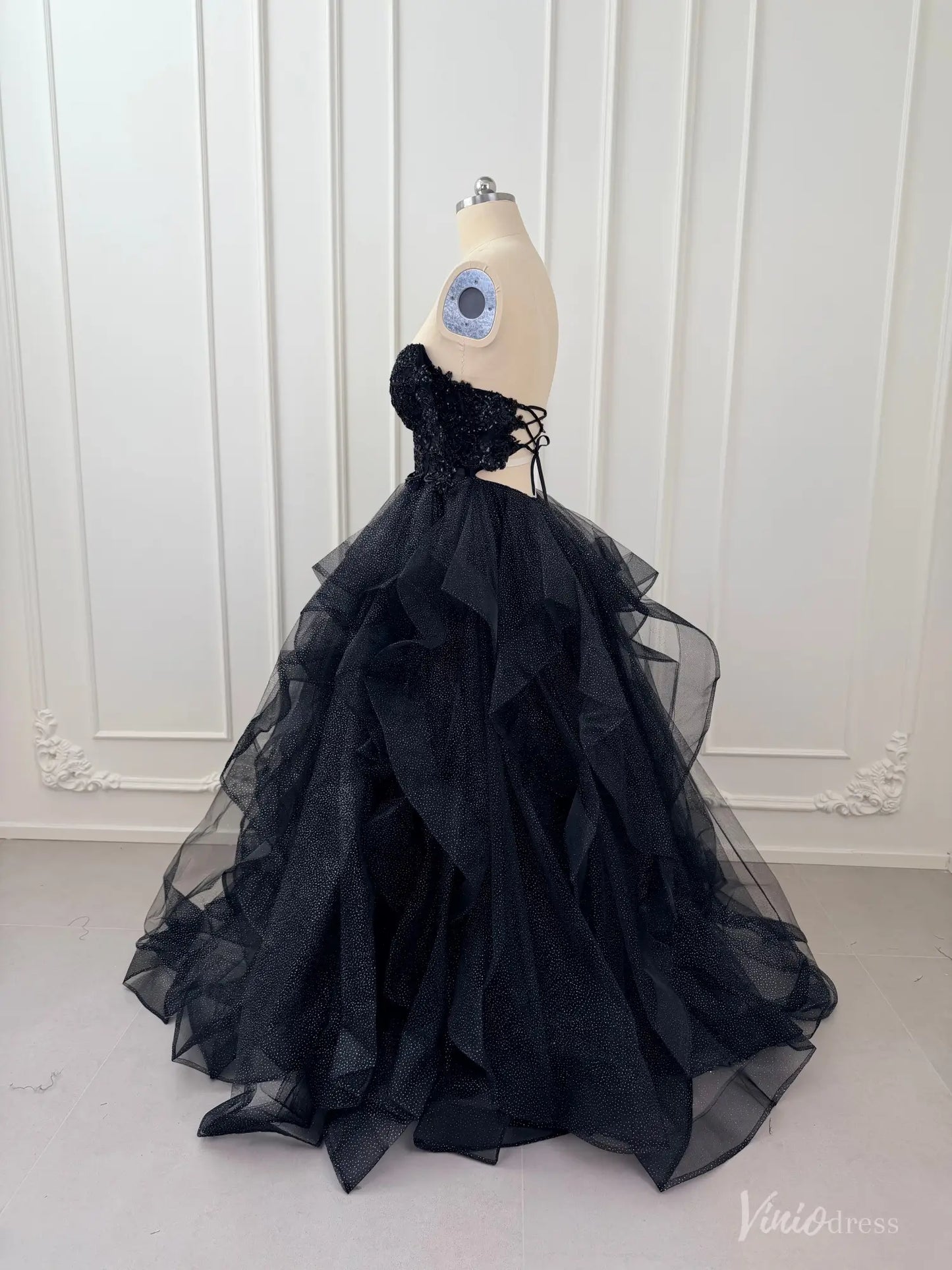 Black glitter tulle ball gown with a corset bodice, lace appliqué, and a voluminous layered ruffle skirt.