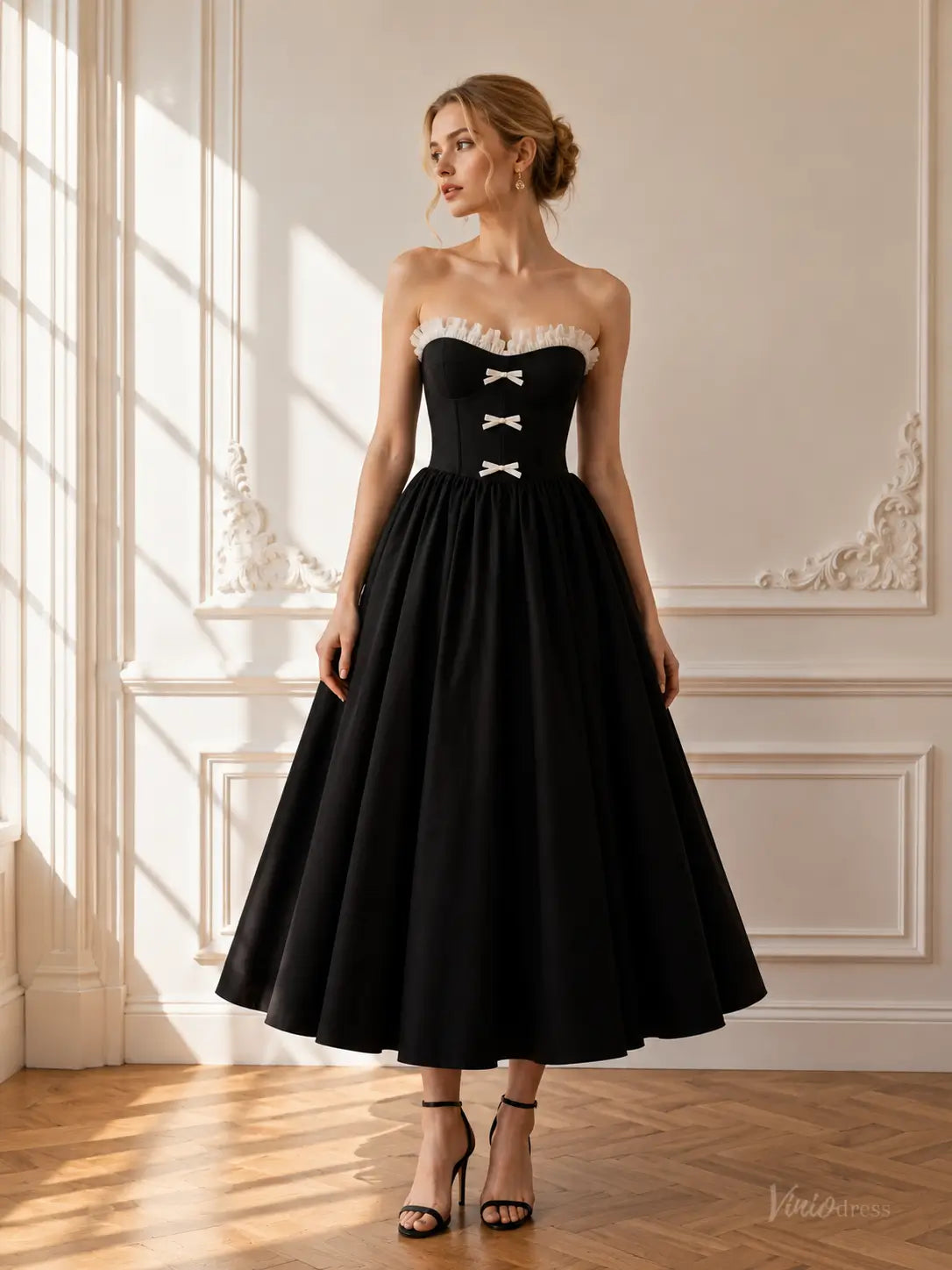 Black tea-length prom dress with a strapless corset bodice, white ruffle neckline, and three front bow details.