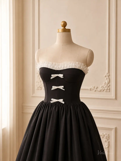 Black tea-length prom dress with a strapless corset bodice, white ruffle trim, and three delicate white bow details.
