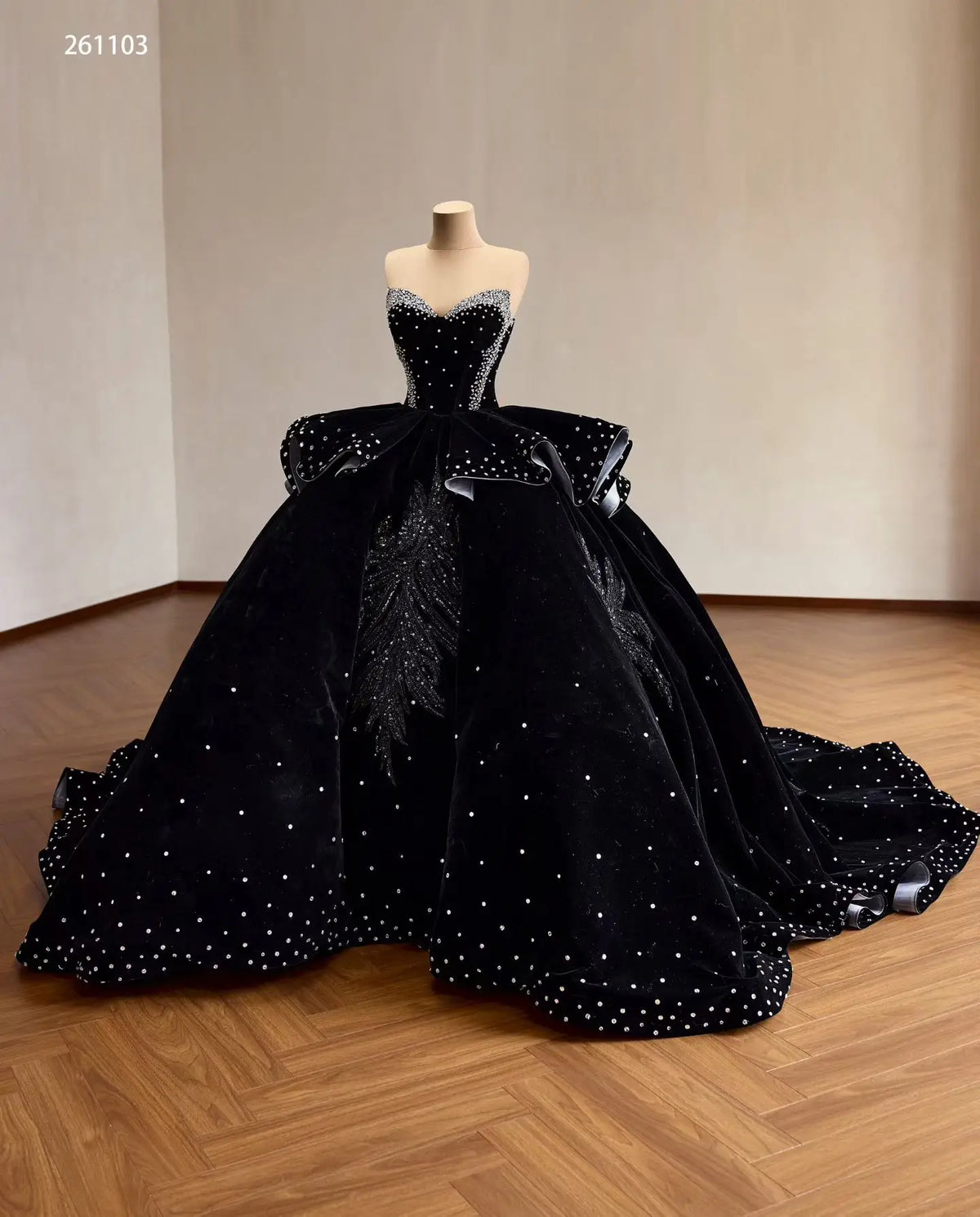 Black velvet quinceañera ball gown with crystal corset, ruffle peplum, and beaded leaf embroidery on a full sweeping skirt.