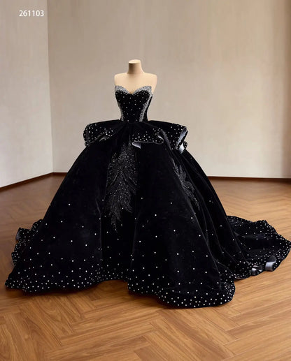 Black velvet quinceañera ball gown with crystal corset, ruffle peplum, and beaded leaf embroidery on a full sweeping skirt.