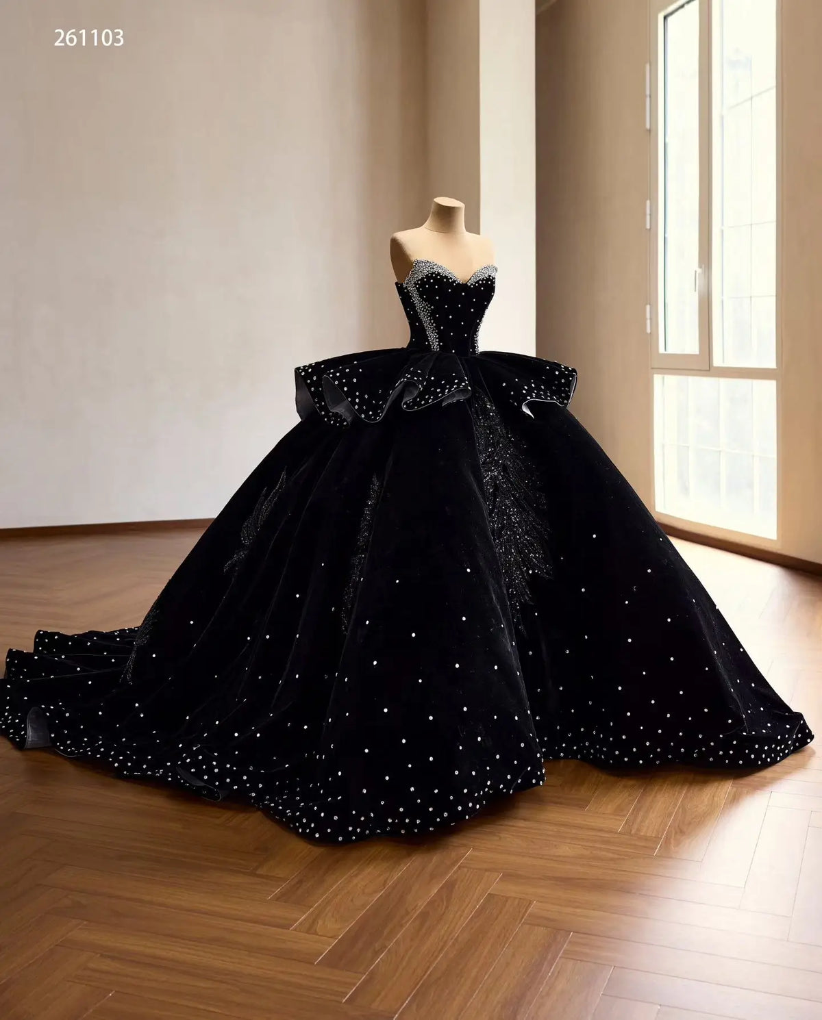 Black velvet quinceañera ball gown with crystal corset, ruffle peplum, and beaded leaf embroidery on a sweeping train.