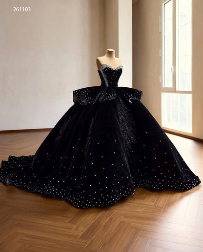 Black velvet quinceañera ball gown with crystal corset, ruffle peplum, and beaded leaf embroidery on a sweeping train.