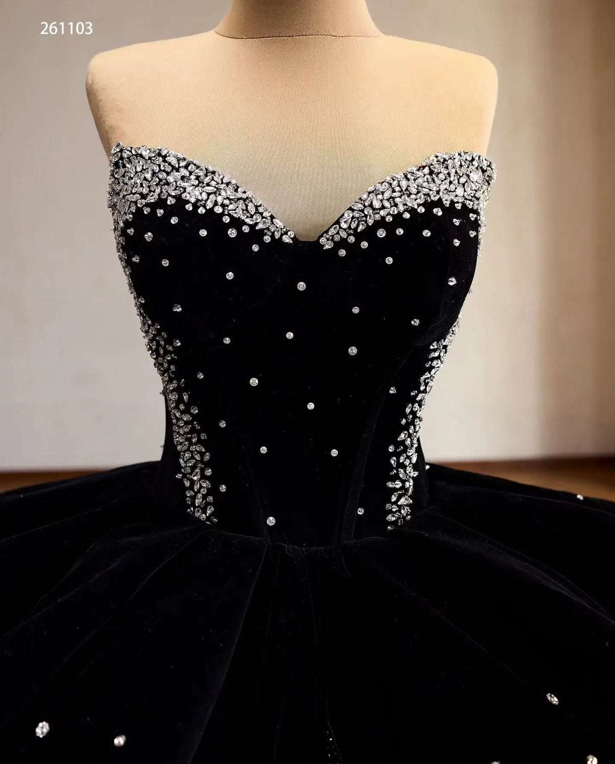 Black velvet quinceanera dress with a crystal-embellished sweetheart corset, sculptural peplum, and scattered rhinestones.