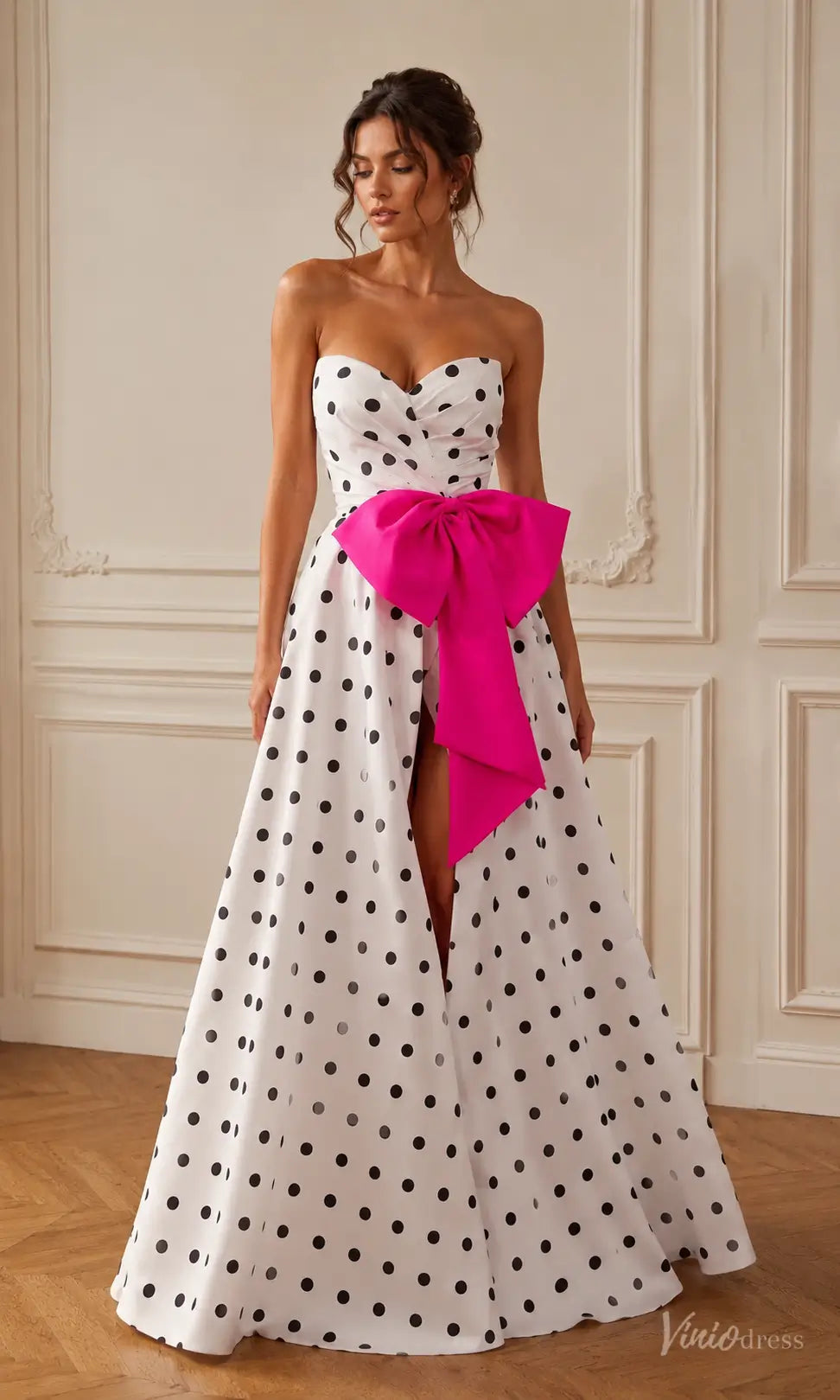 Strapless white polka dot prom dress with a sweetheart bodice, high front slit, and a large hot pink satin waist bow.