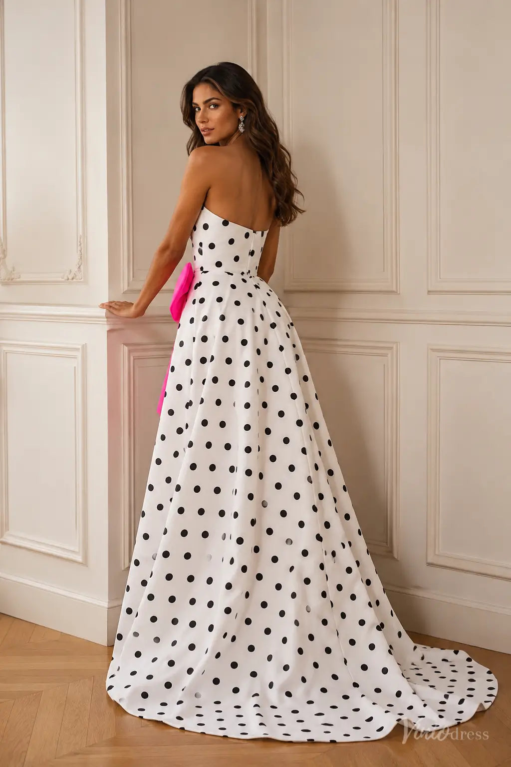 Strapless white prom dress with black polka dots, featuring a structured sweetheart bodice and a large pink satin waist bow.