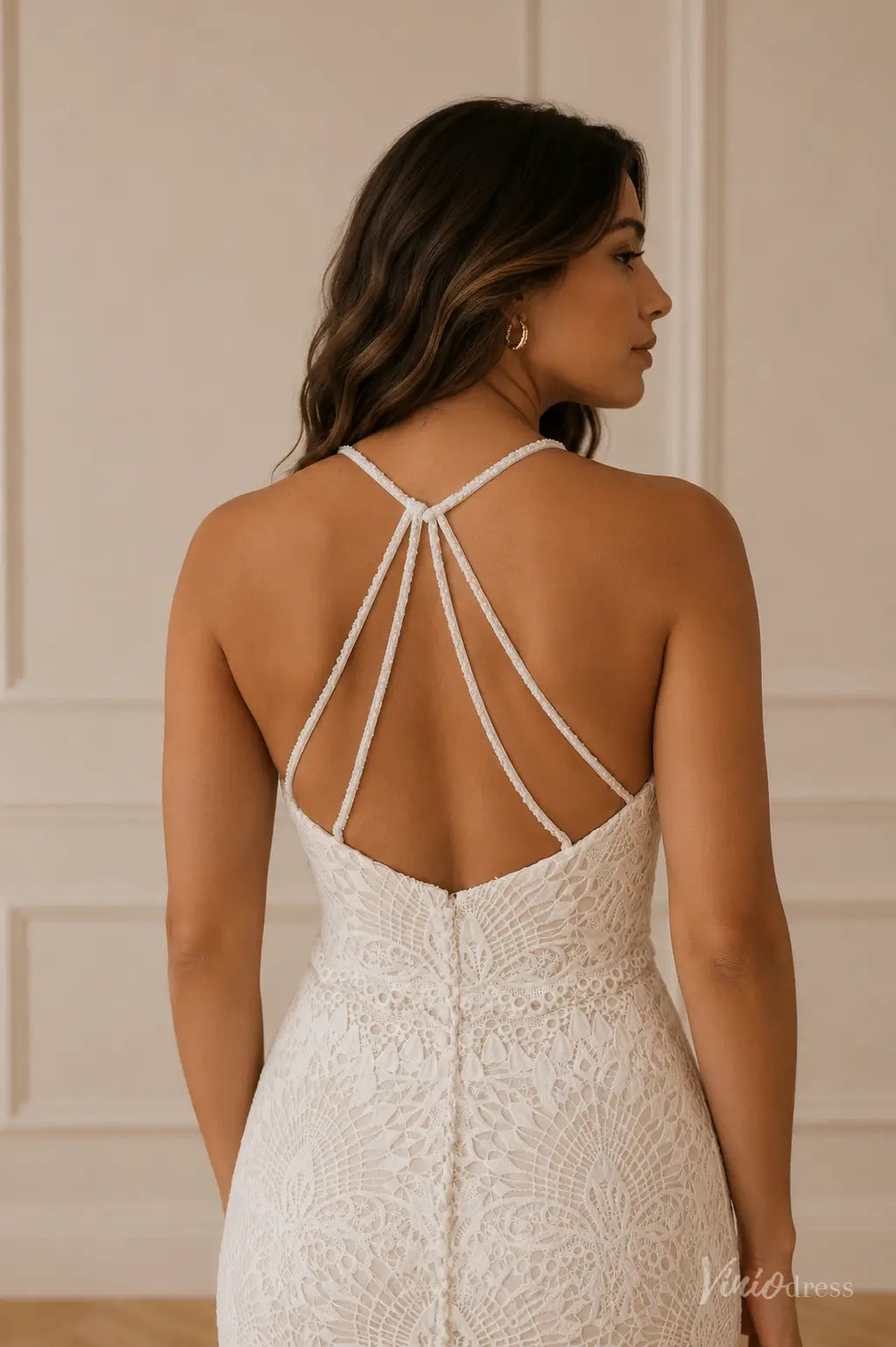 White lace wedding dress with a low back, delicate spaghetti straps, and elegant button-down detailing.