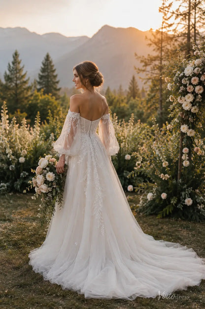 Boho wedding dress with puff sleeves, pleated bodice, floral lace appliqués, and chapel train in a garden setting.
