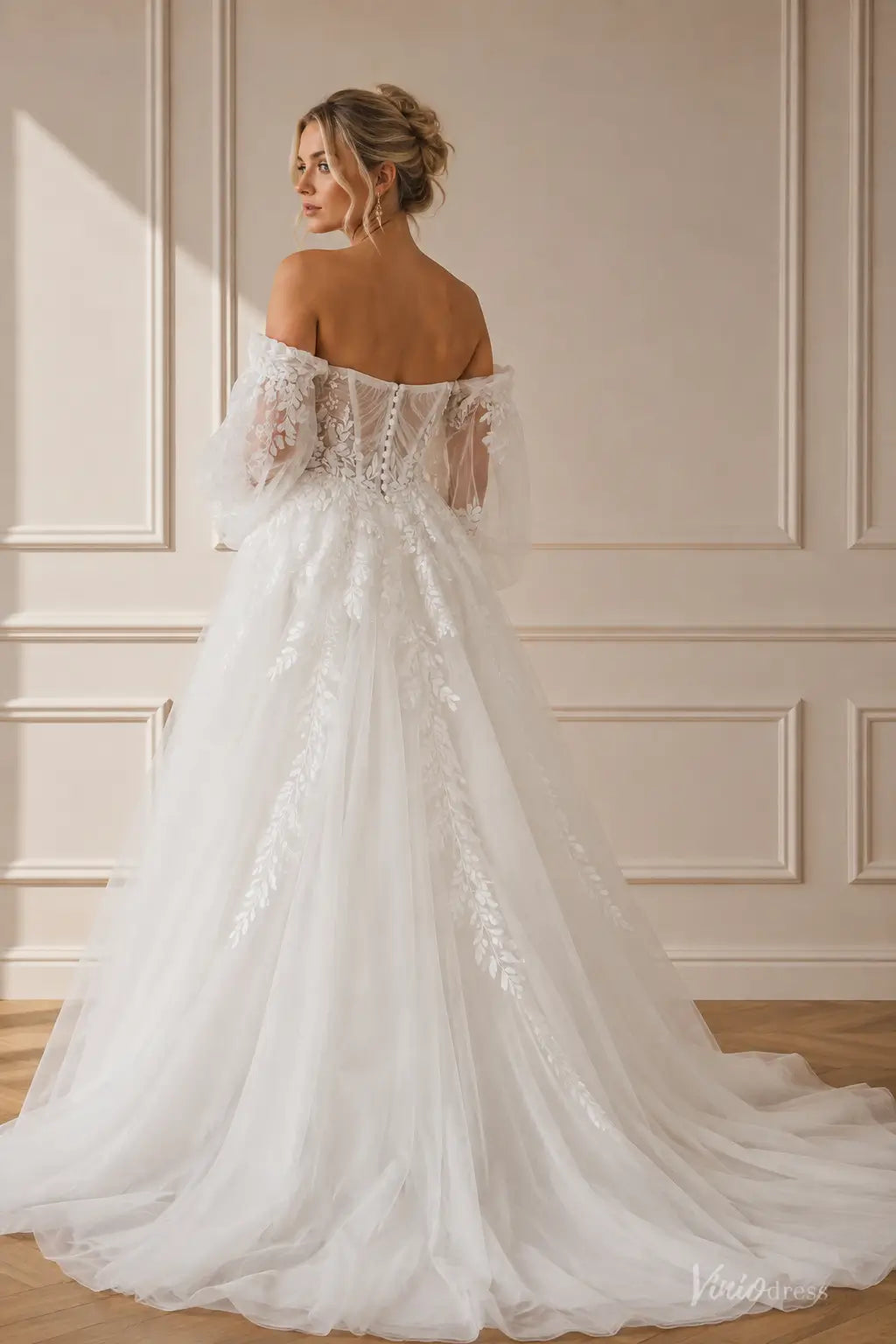 Boho wedding dress with puff sleeves, pleated bodice, floral lace appliqués, and a flowing chapel train in white tulle.
