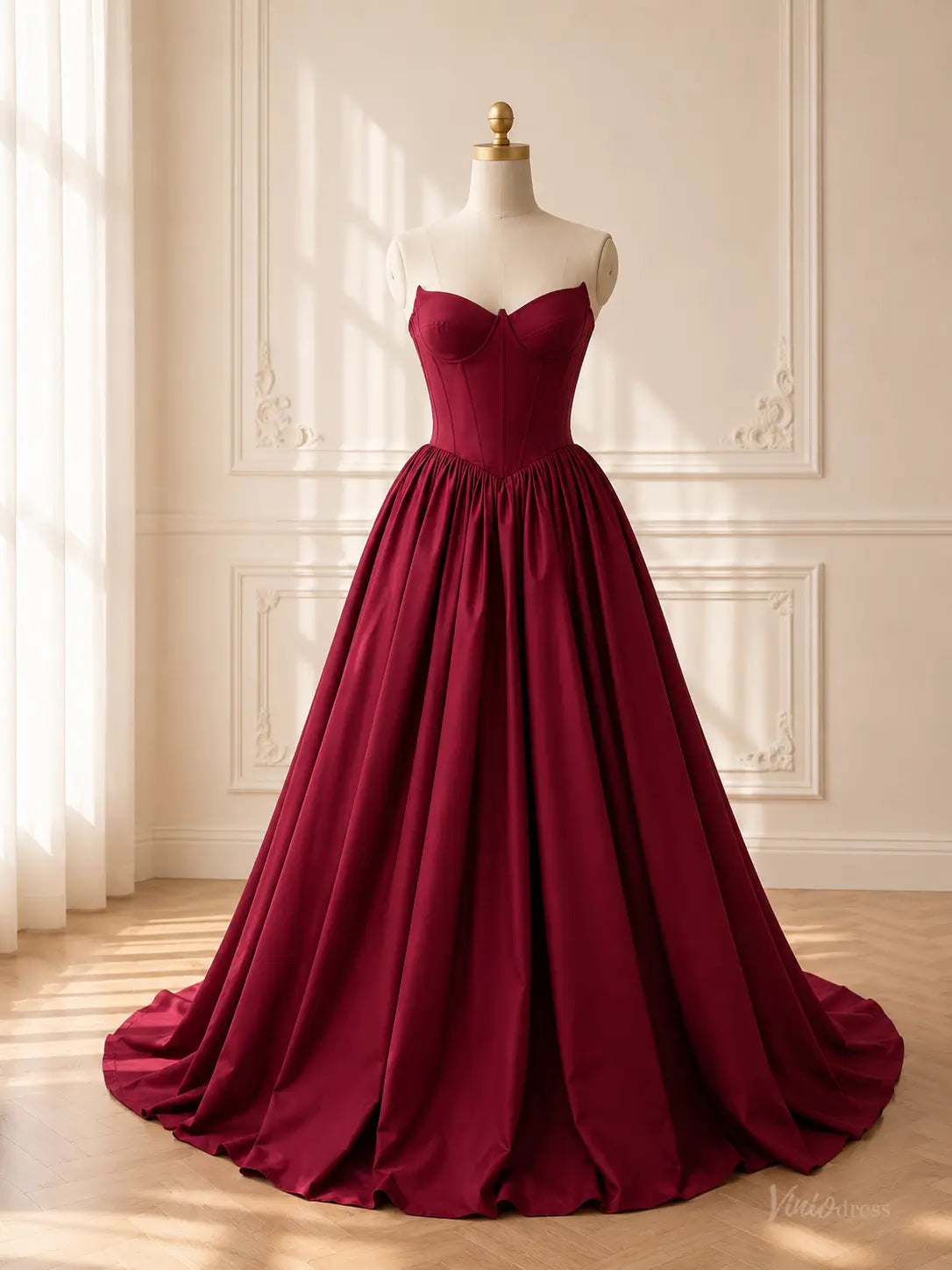 Burgundy satin ball gown with a strapless sweetheart corset bodice and a dramatic, voluminous gathered skirt.
