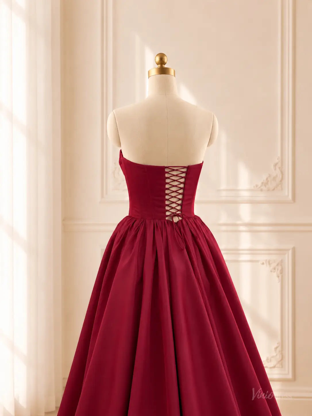 Burgundy satin ball gown with a strapless corset bodice, lace-up back, and voluminous gathered floor-length skirt.