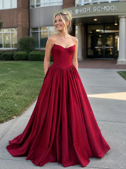 Burgundy satin ball gown with a strapless corset bodice, sweetheart neckline, and a voluminous floor-length skirt.