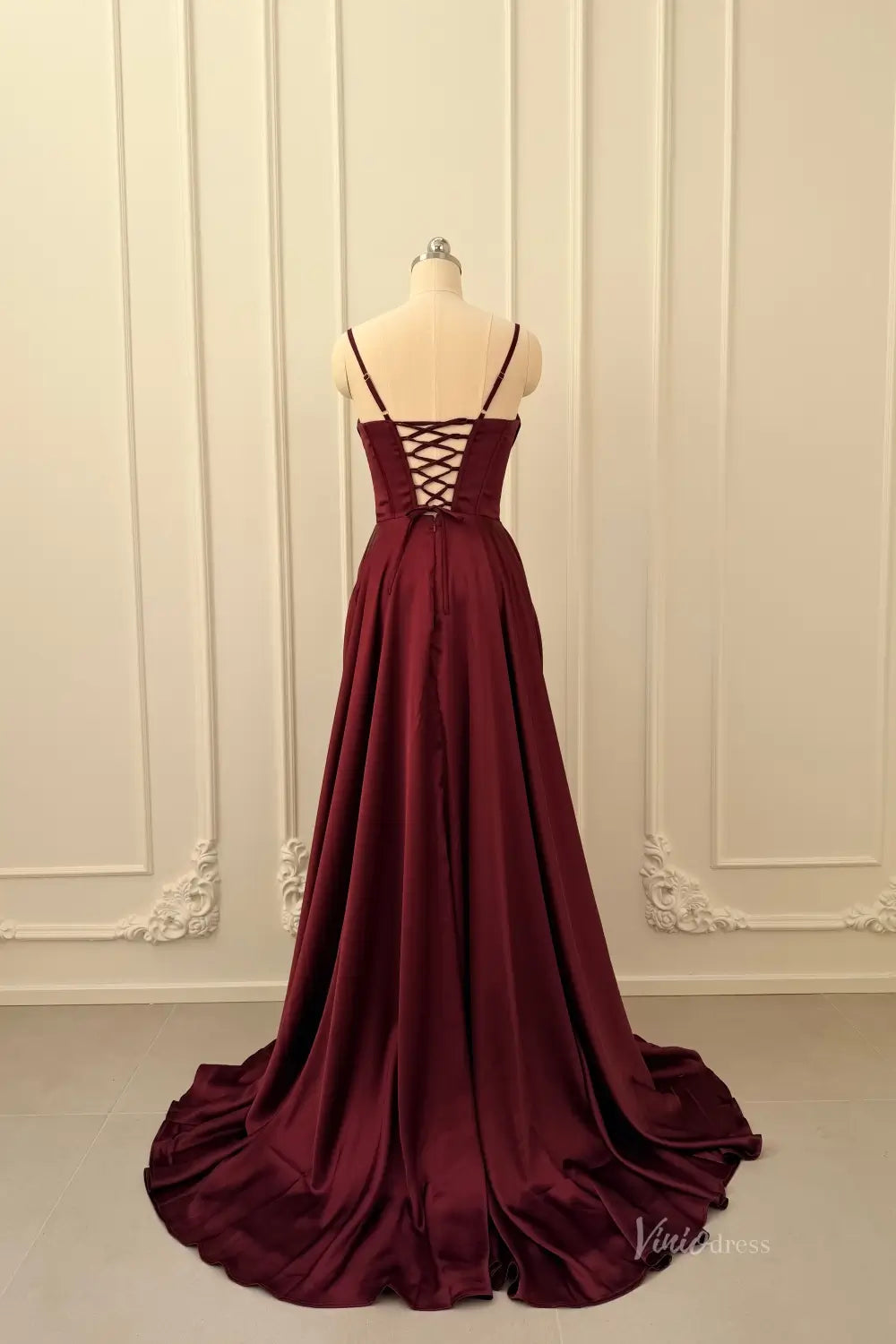 Burgundy satin prom dress with lace-up corset back and spaghetti straps on a mannequin.