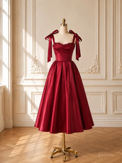 Burgundy satin tea-length prom dress with a corset bodice, draped neckline, and tie bow shoulder straps on a mannequin.