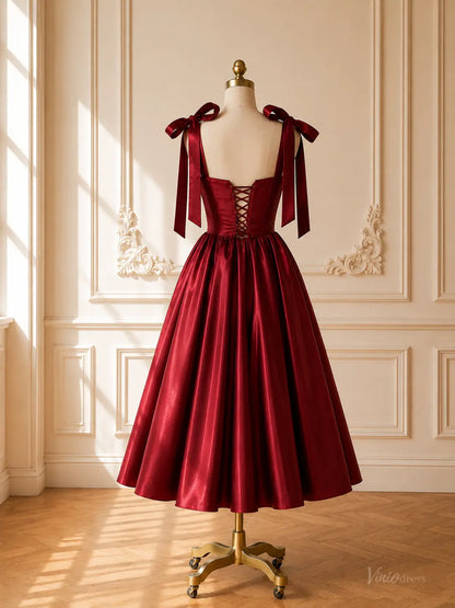 Burgundy satin tea-length prom dress with a lace-up corset back and bow shoulder straps on a mannequin.