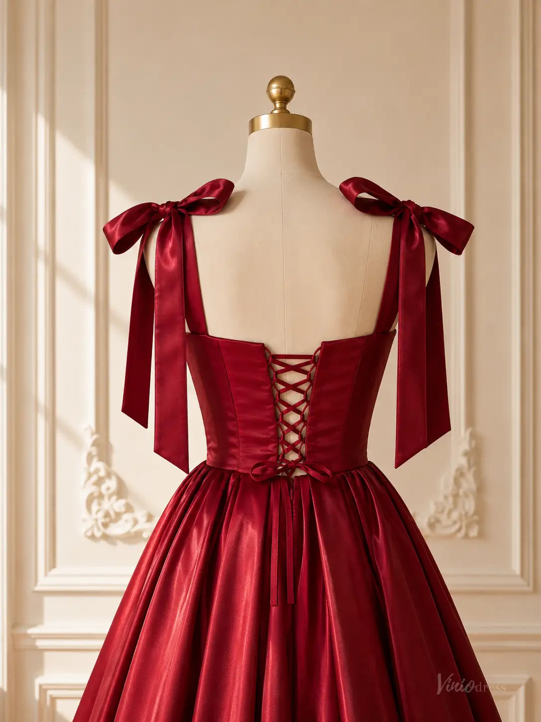 Burgundy satin tea-length prom dress featuring a lace-up corset back and elegant bow shoulder straps on a mannequin.