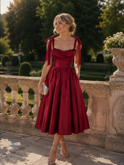 Burgundy satin tea-length prom dress with a corset bodice, draped neckline, and tie bow shoulder straps.