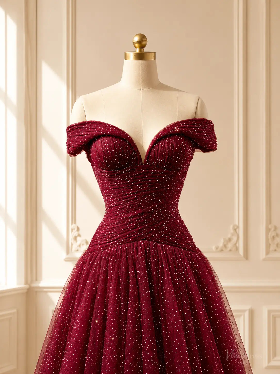 Burgundy sparkly tulle ball gown with an off-shoulder sweetheart neckline and ruched bodice on a dress form.