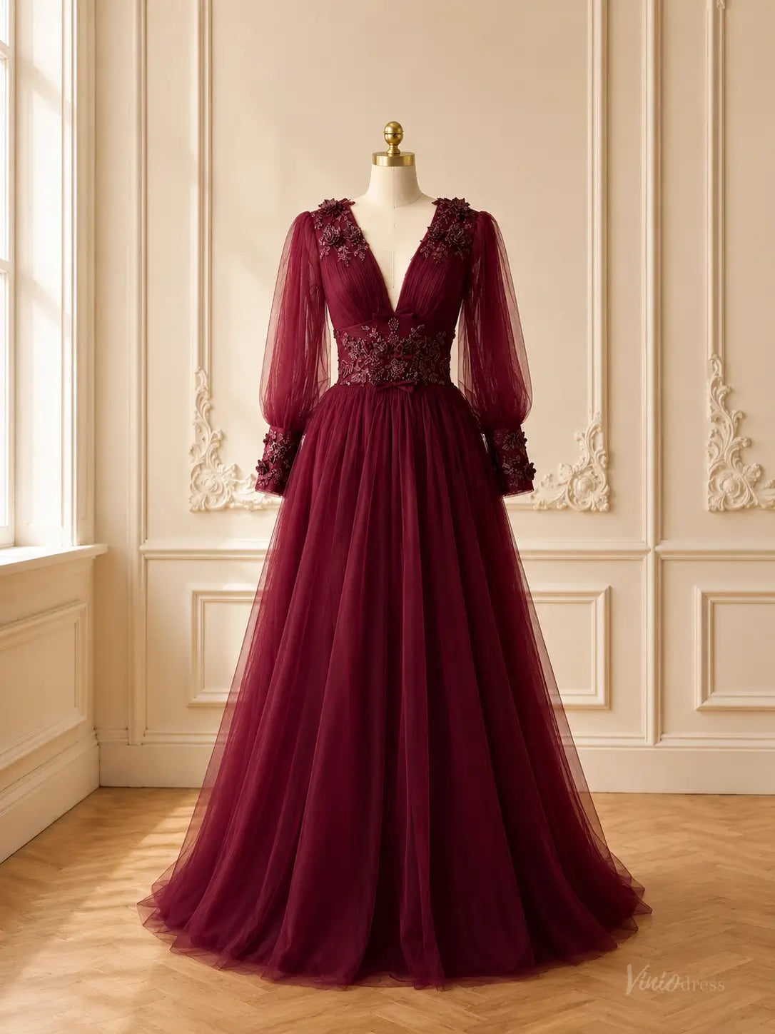 Burgundy tulle A-line prom dress with deep V-neck, sheer bishop sleeves, and floral lace appliqués on a mannequin.