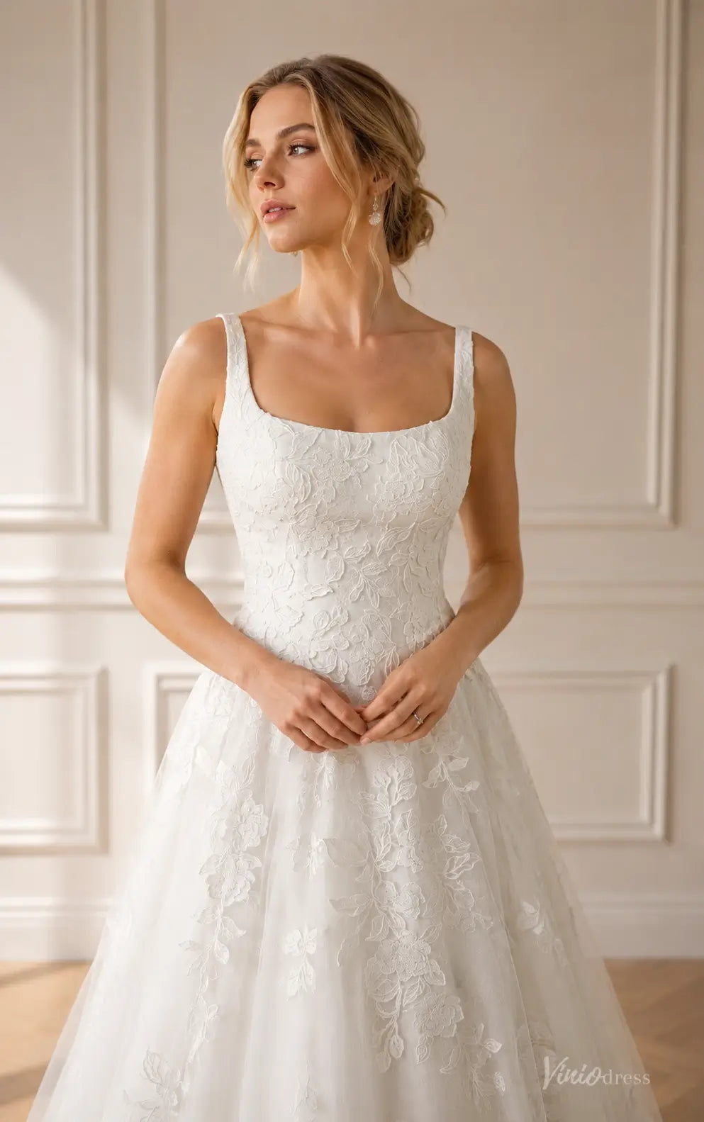 White A-line wedding dress featuring a square neckline and intricate floral lace embroidery on tulle fabric.