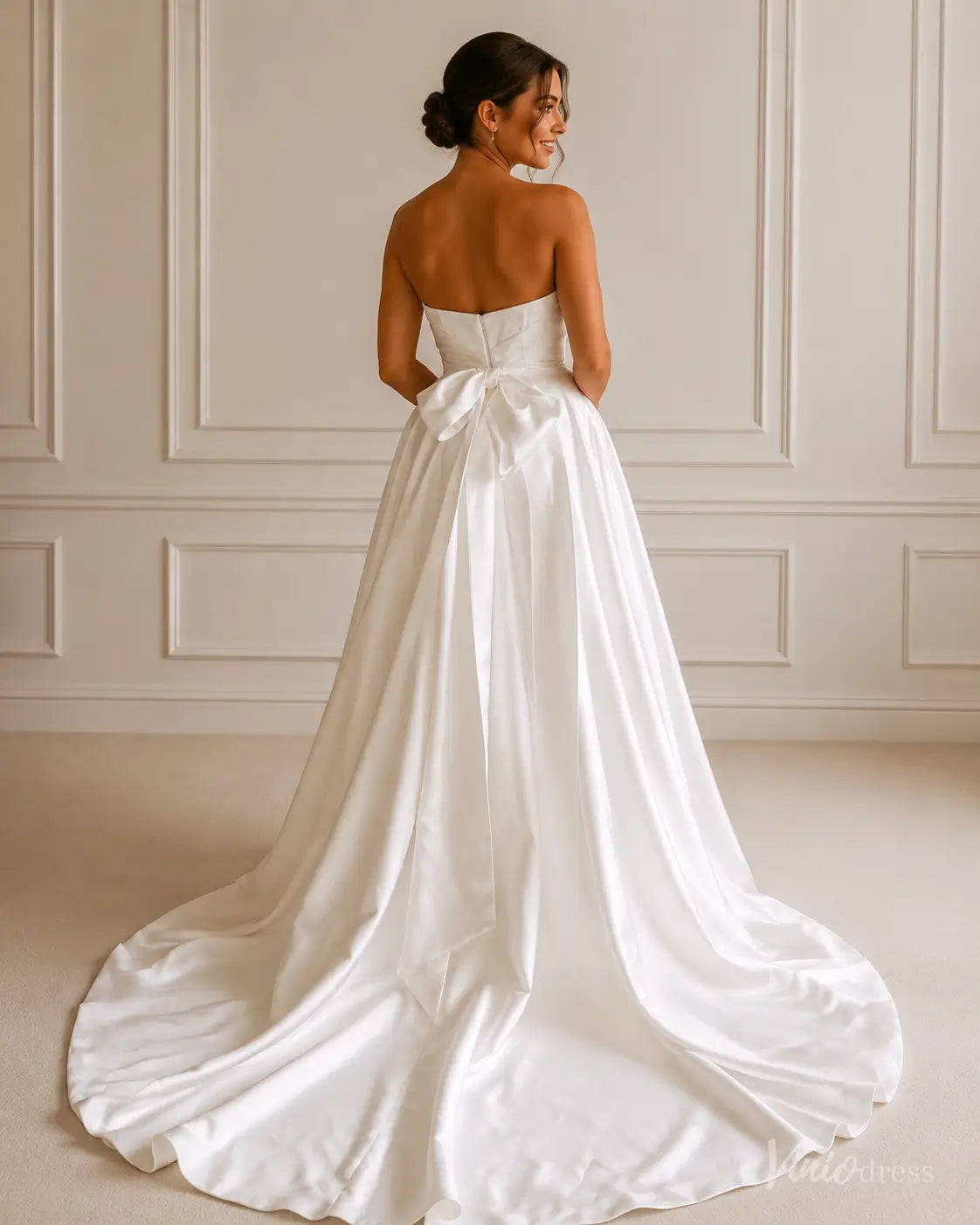 Strapless white satin A-line wedding dress with a fitted bodice and a dramatic floor-length train featuring a back bow.