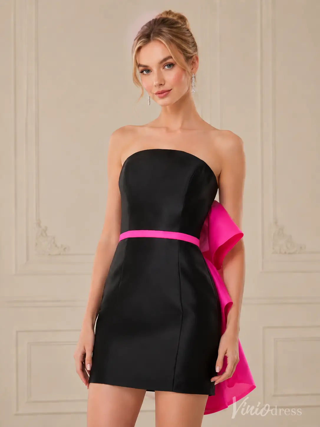 Black strapless mini dress with a vibrant pink waist belt and a large, flowing pink bow on the side.