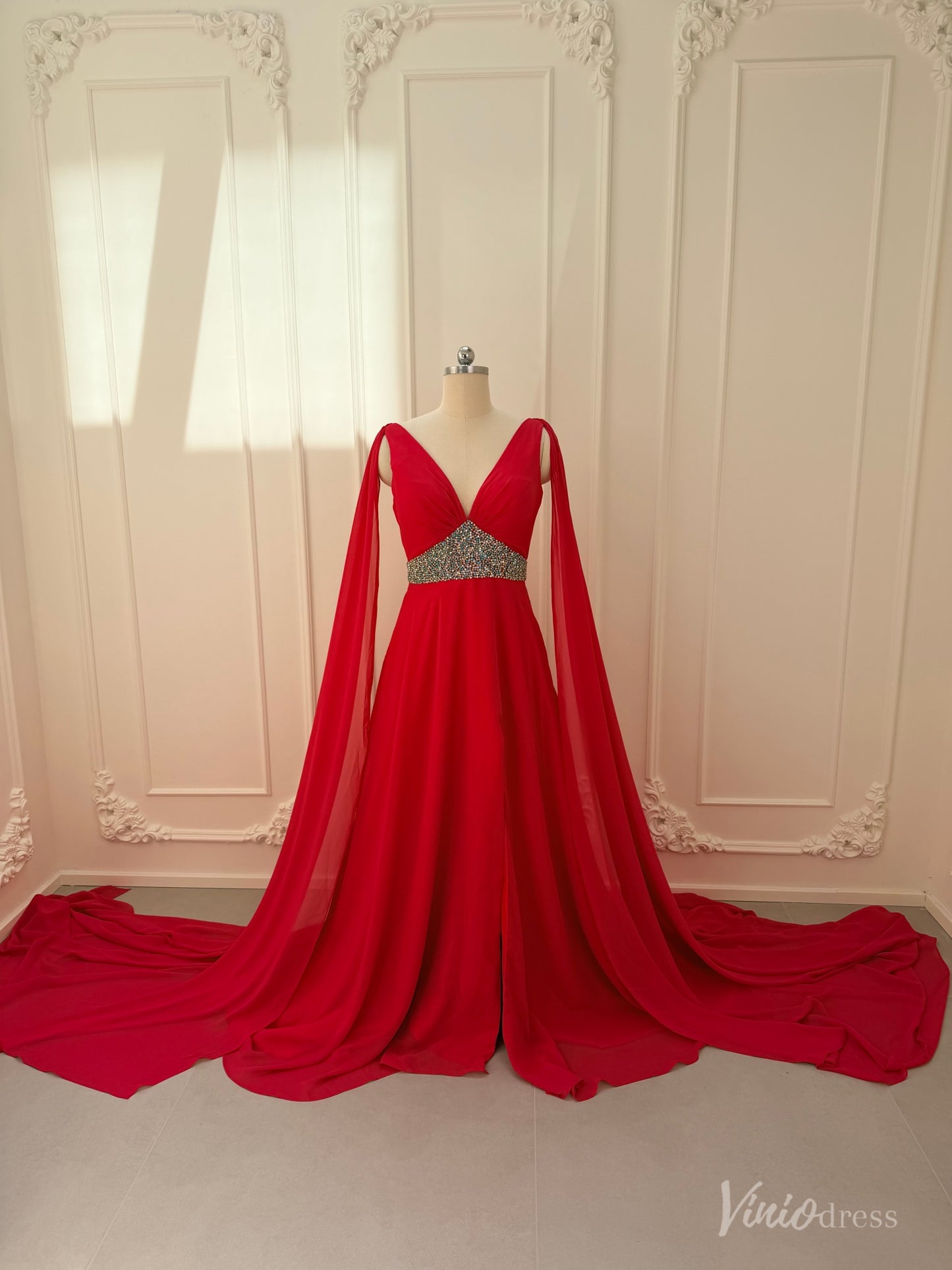 Crimson red chiffon pageant gown with V-neck, dramatic cape sleeves, and a beaded waistline on a mannequin.