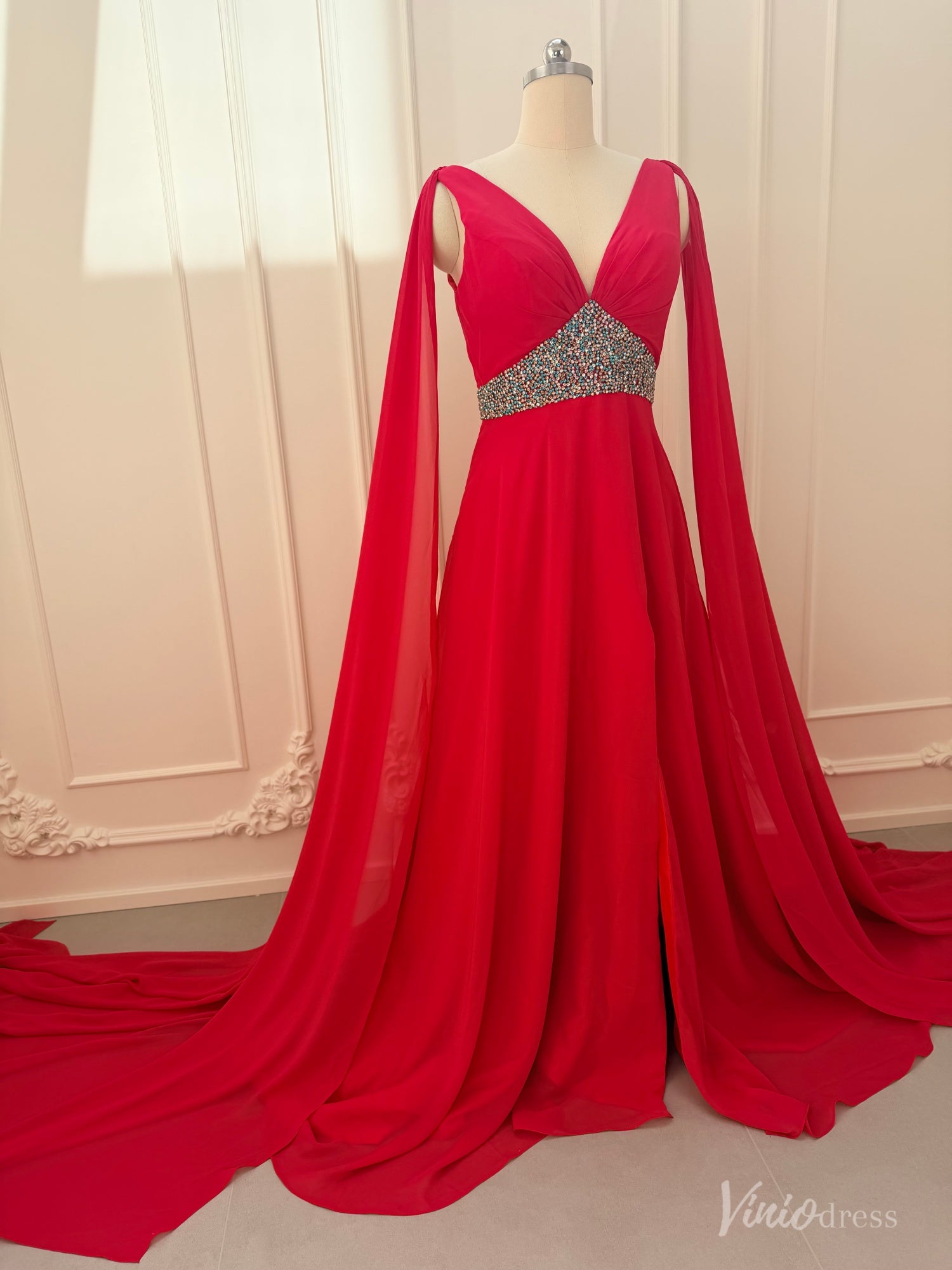 Crimson red chiffon A-line gown with V-neckline, dramatic cape sleeves, and a beaded waistline on a mannequin.