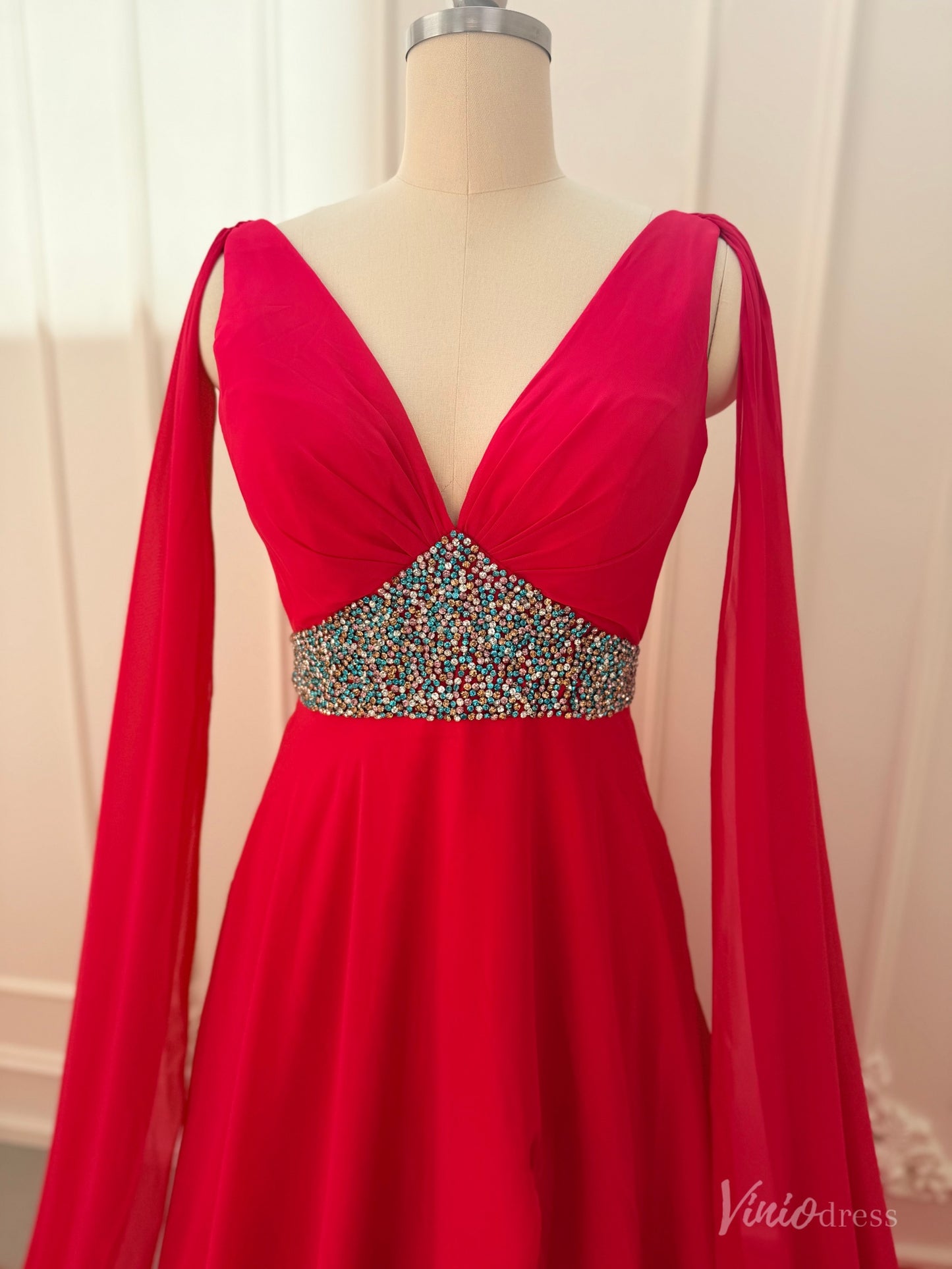 Crimson red chiffon pageant gown with V-neckline, dramatic cape sleeves, and a multi-colored beaded waistline.