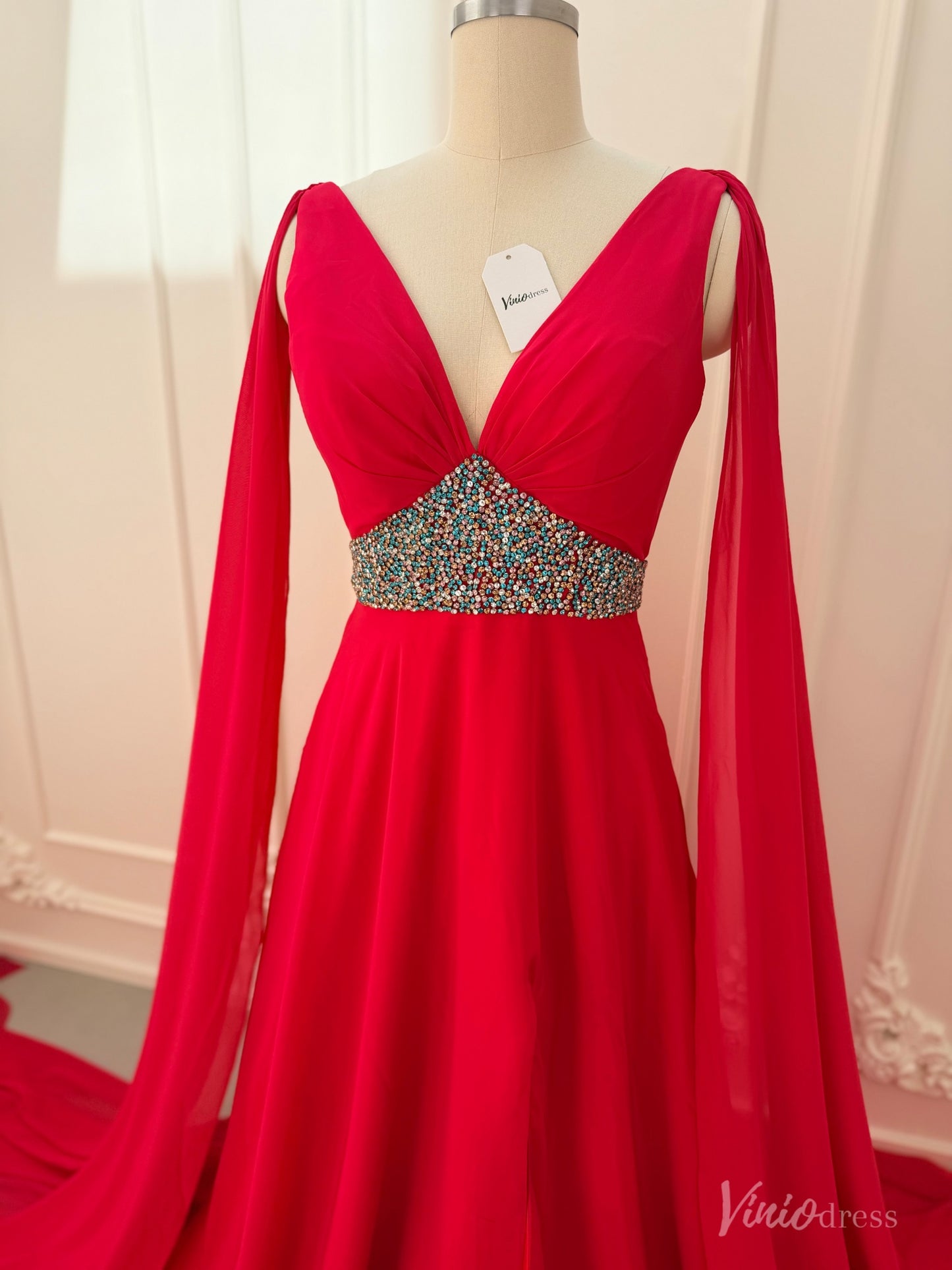 Crimson red chiffon pageant gown with V-neckline, dramatic cape sleeves, and a multi-colored beaded waistline.