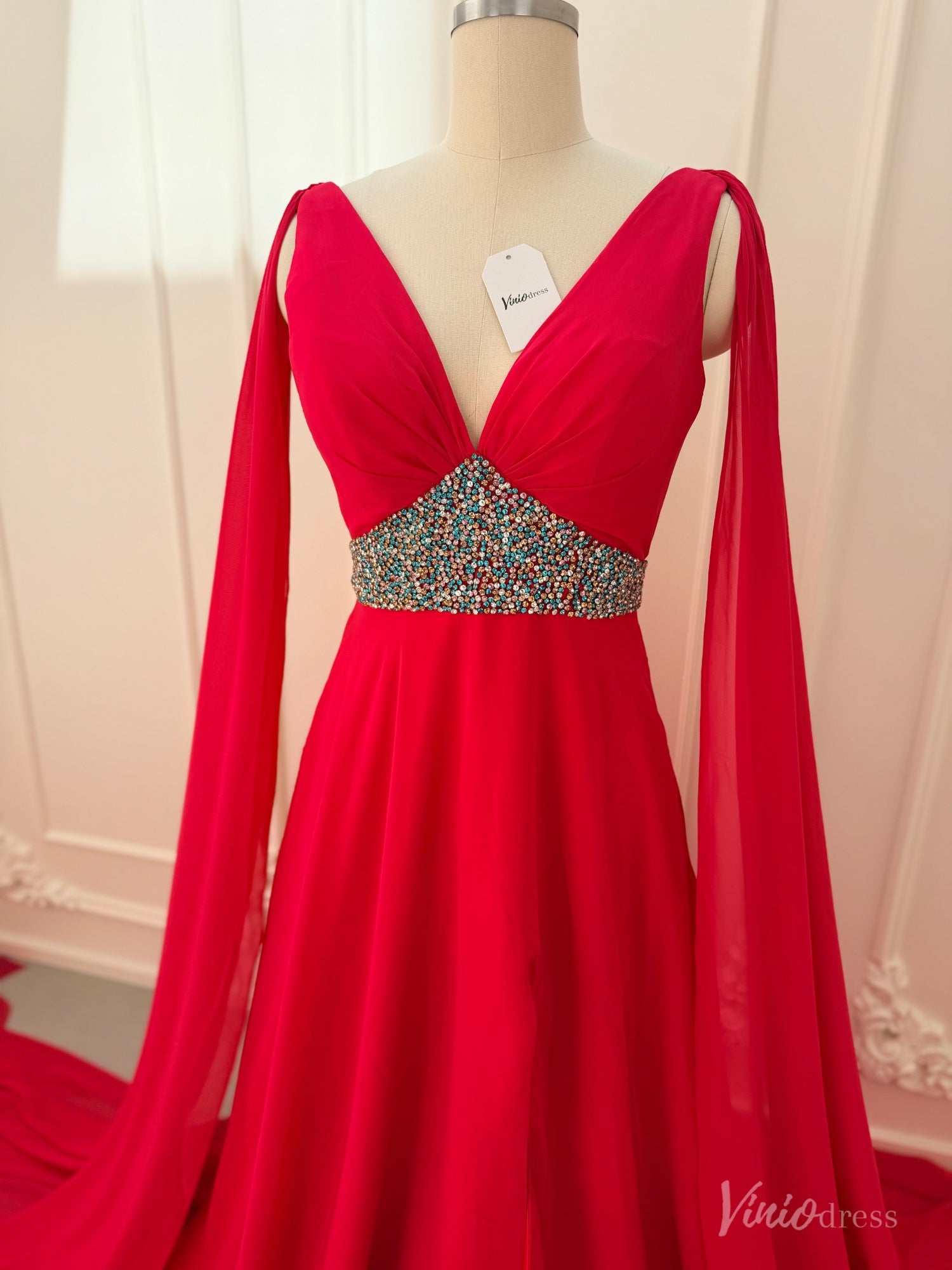 Crimson red chiffon pageant gown with V-neckline, dramatic cape sleeves, and a multi-colored beaded waistline.