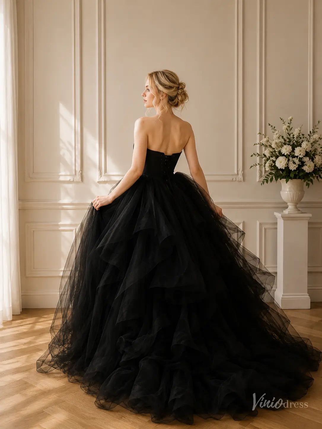 Strapless black wedding gown featuring a corset bodice and a dramatic, voluminous layered tulle ball gown skirt.