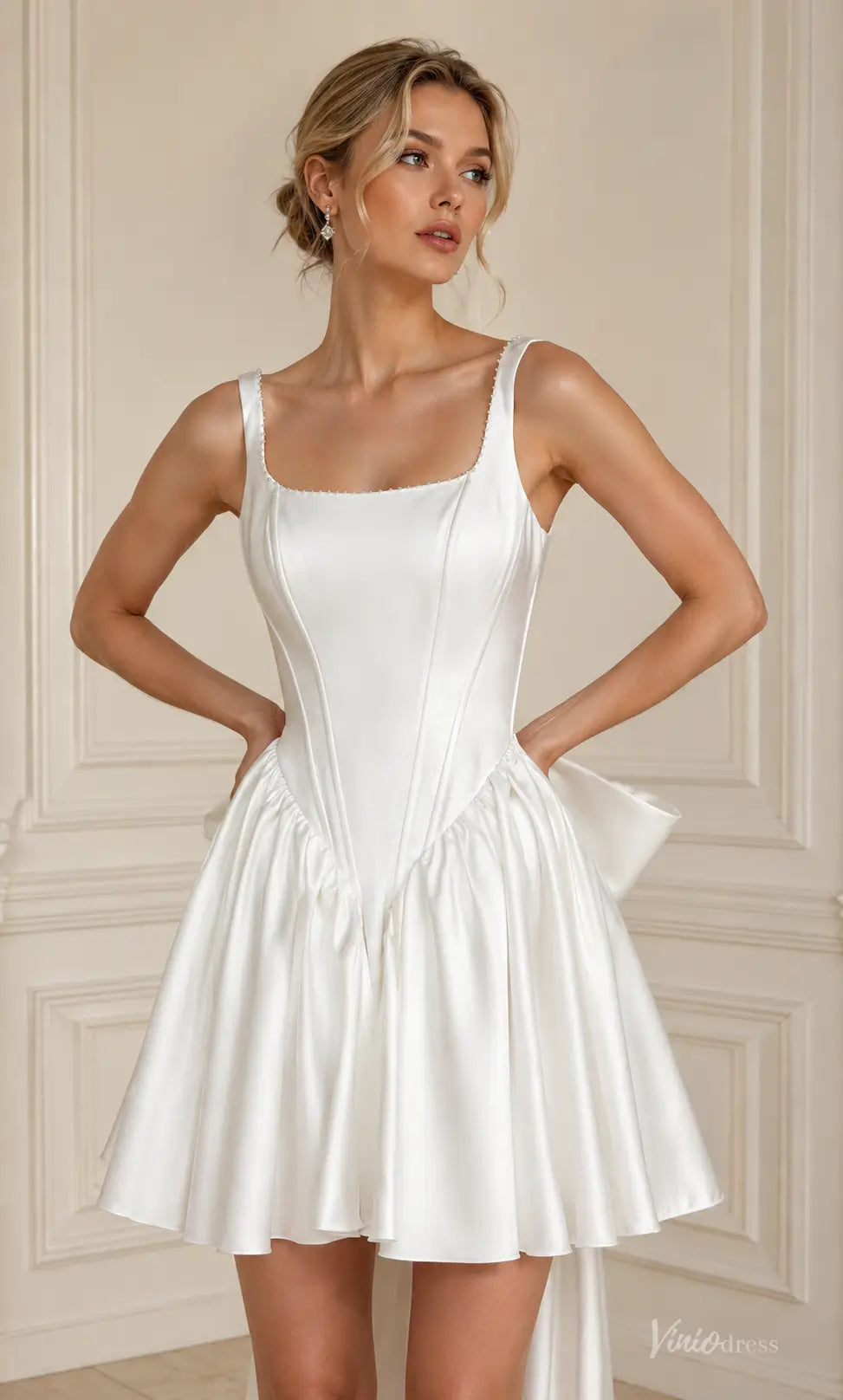 White satin mini wedding dress with a square neckline, corset-style bodice, and a voluminous flared skirt.